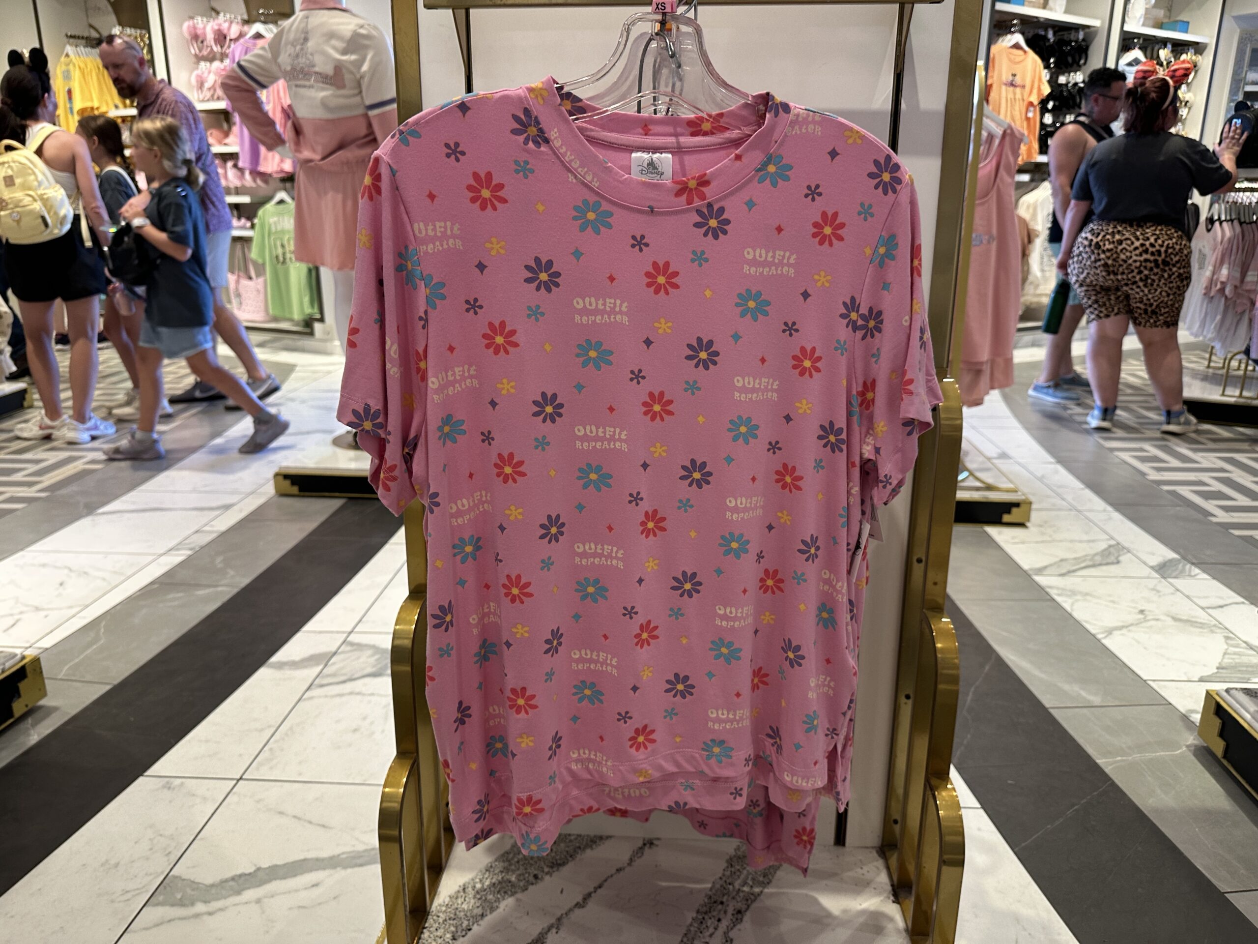 In a bright pink, this short-sleeved and shorts sleep set has blue, purple, yellow, and pink flowers and stars throughout. It also says "outfit repeater" and is themed to Lizzie McGuire.