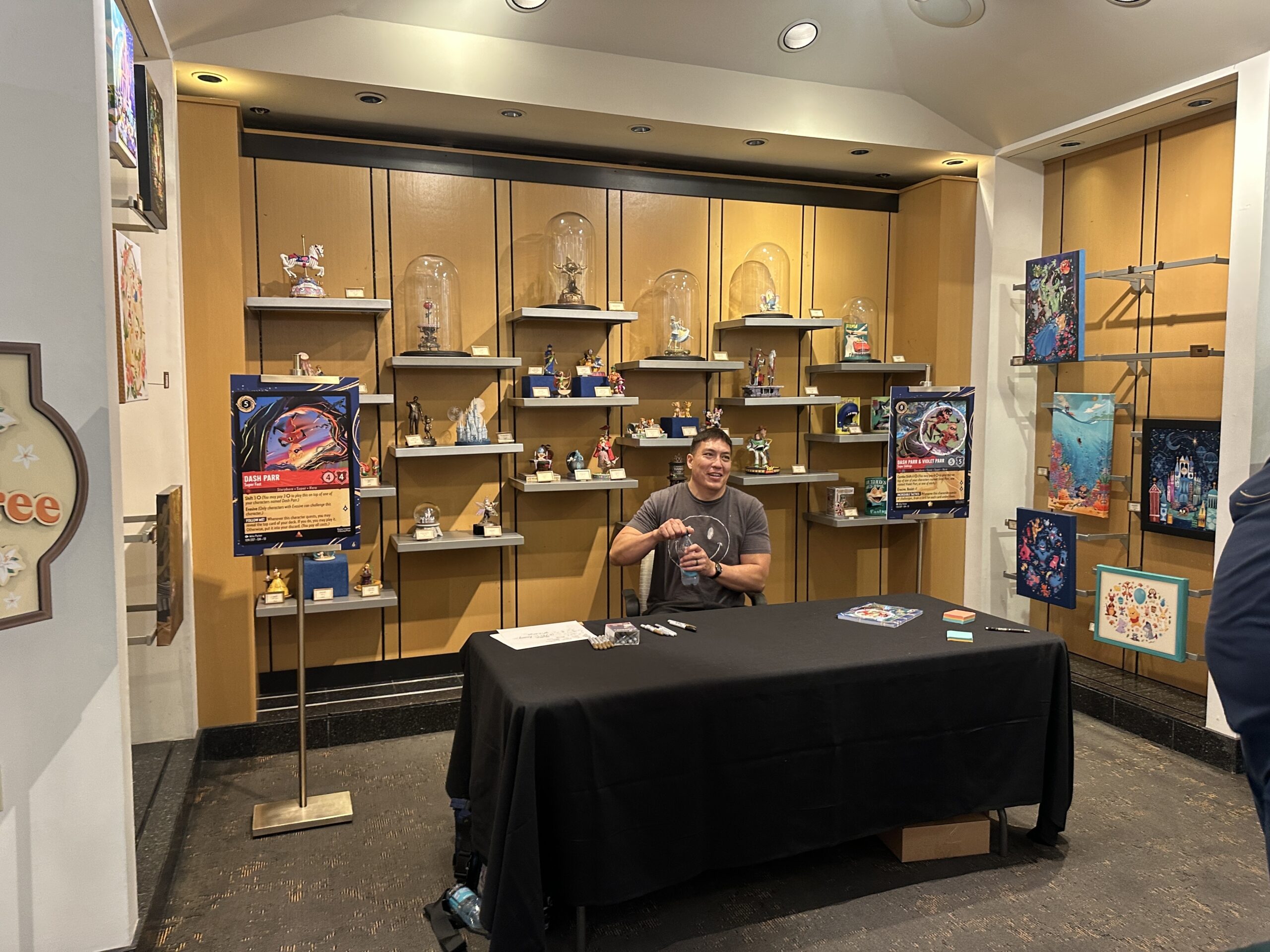 Parker was set up among artwork in the shop with an enlarged version of one of his Lorcana card designs on either side.