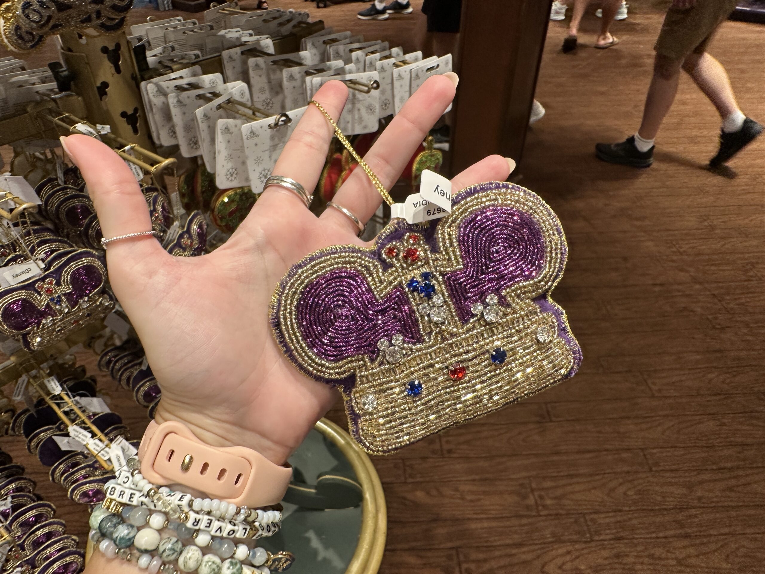 A Mickey version of the UK's Imperial State Crown, this one is shaped like a Mickey ear hat. The plush ornament his heavily beaded with purple and gold details. There are also rhinestone embellishments and hidden Mickeys in red, blue, and clear.