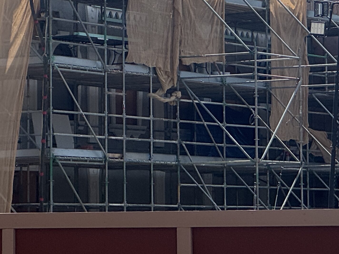 While it is difficult to see with the scrim draping, the archways around the windows are getting a monstrous treatment. The white trim around them has triangular spikes on the top which resemble horns. But decorative trim has also appeared beyond the windows. As you can see above, there are decorative elements on the beams to make them look like steel and the trim at the top is scalloped.