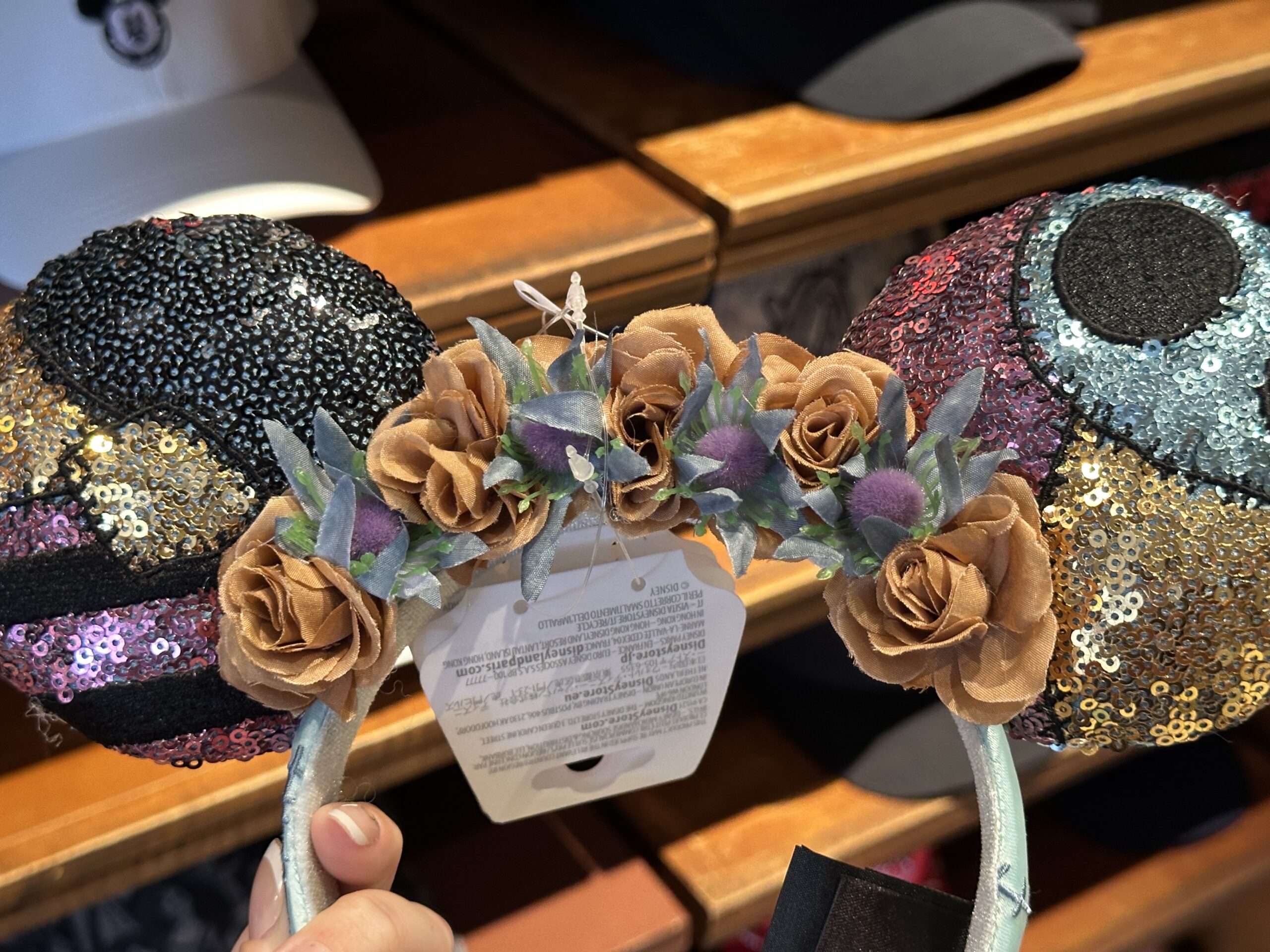 Rather than a bow in the middle, there are flowers as if adorning a flower crown. These flowers in shades of dull amber and muted purples and greens, similar to the look of dried fresh flowers as they decay.