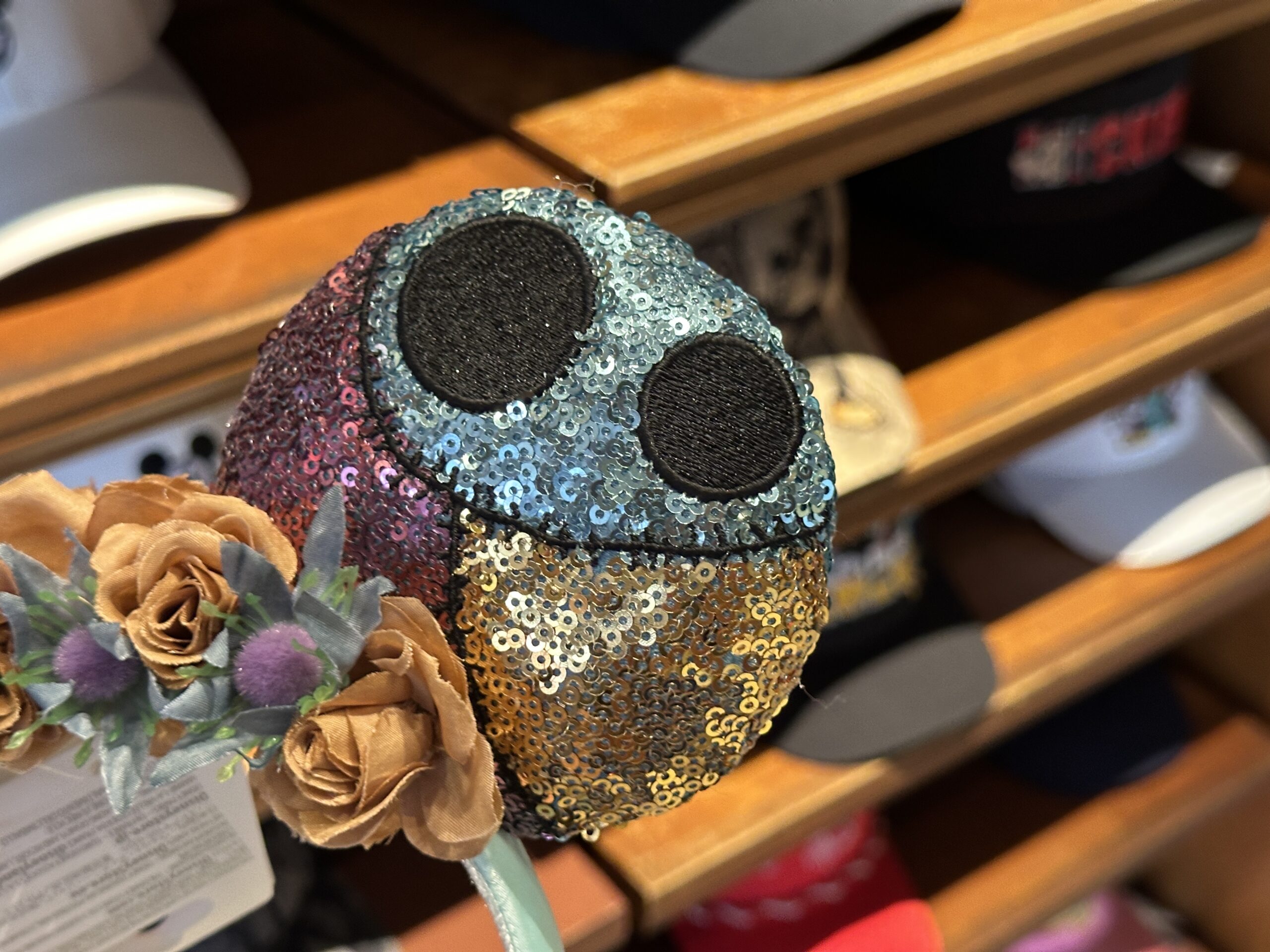 The left ear shows sequins in gold, pink, and light blue with two black embroidered dots that appear on a section of Sally's dress.