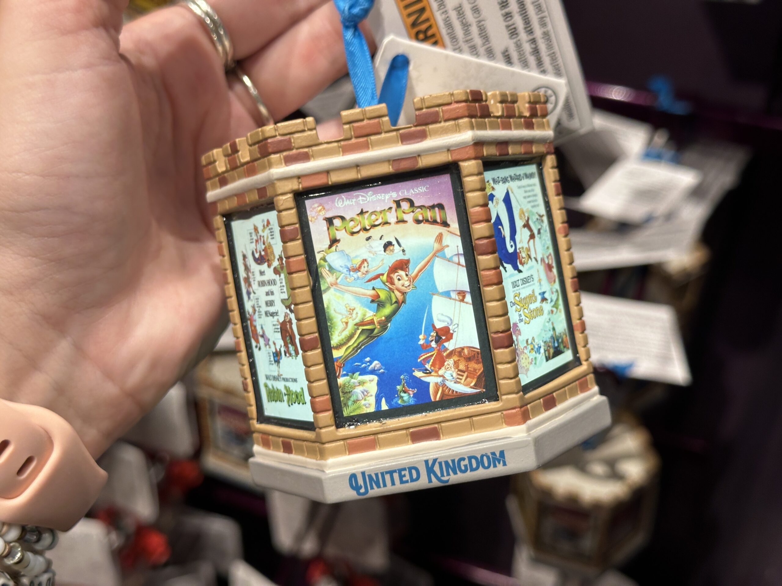 This six-sided, light-up ornament celebrates classic Disney films that took place in England. Each side has a different vintage poster from the film. These include Peter Pan, The Sword in the Stone, One Hundred and One Dalmatians, Icabod and Mister Toad, Alice in Wonderland, and Robin Hood. The ornament is designed like the top of a castle tower.