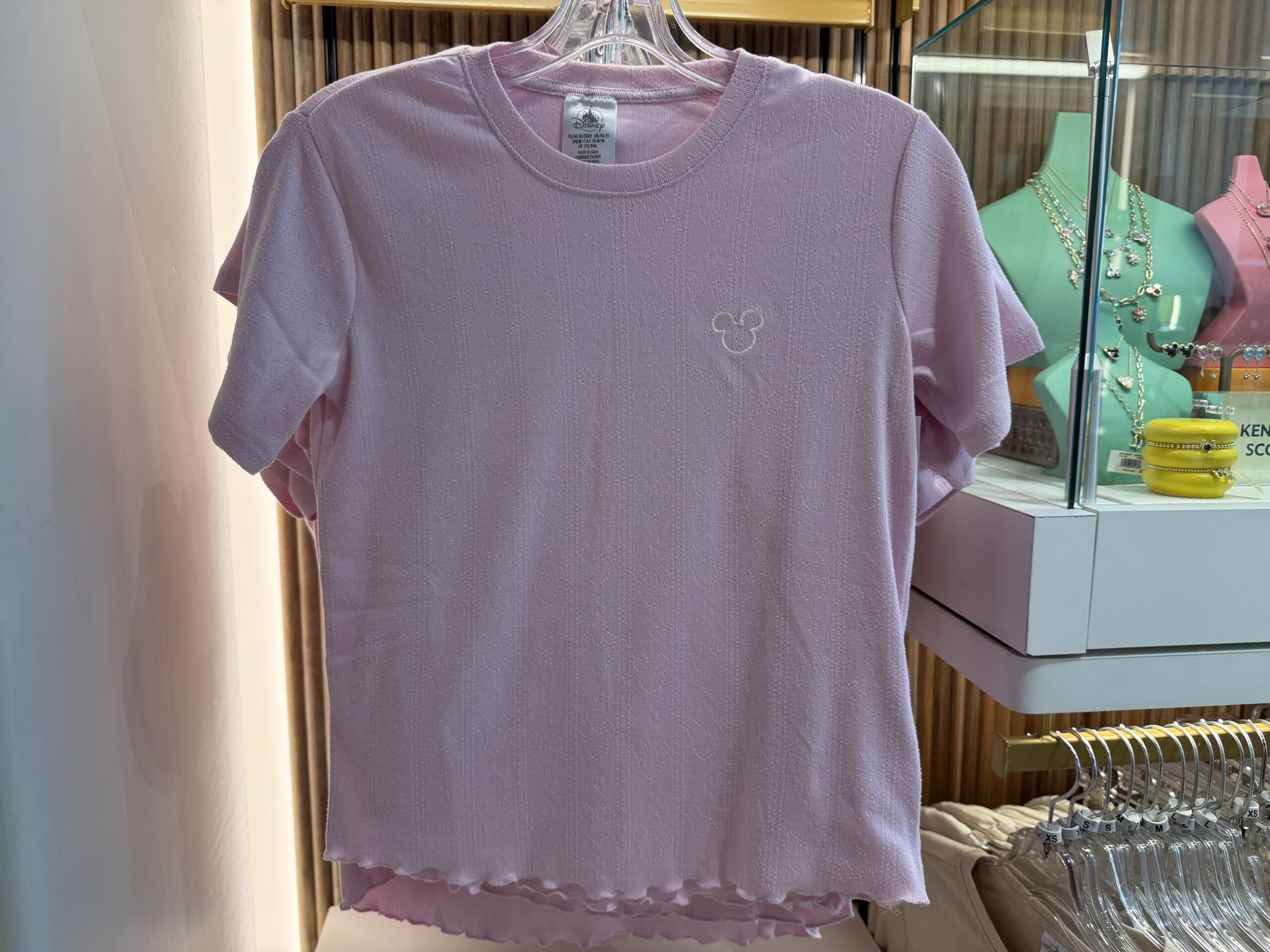 With a ruffled waist and leg hems, this two-piece sleep set comes with matching shorts and T-shirt. They are both in light pink, and the top has a small, white Mickey head icon on the left side of the chest.