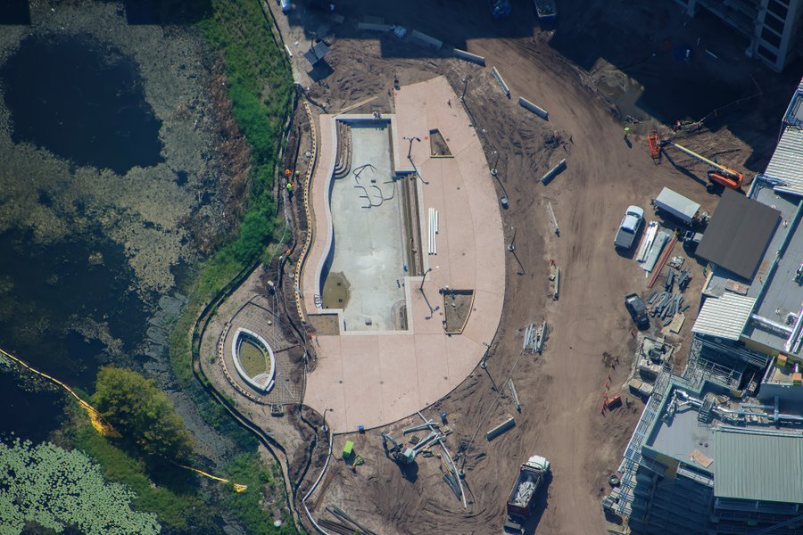 There appear to be light poles in place around the pool deck, which was paved last month, though we cannot be sure from photos if they are temporary lights or permanent ones.