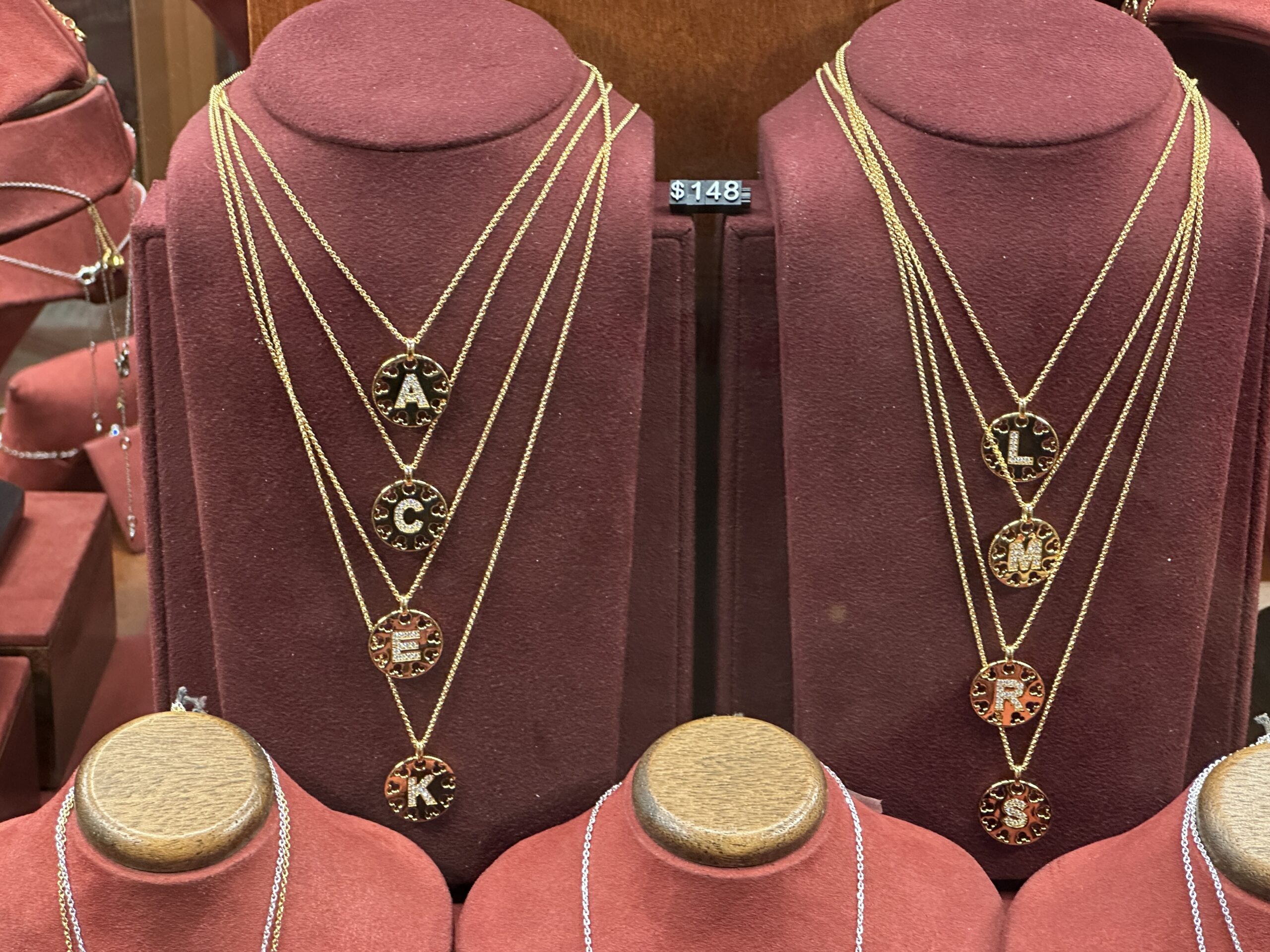 These gold-tone necklaces come in eight varieties that we saw on display for the letters: A, C, E, K, L, M, R, and S. Each initial is in a circle that is surrounded by Mickey-icon-shaped cutouts.