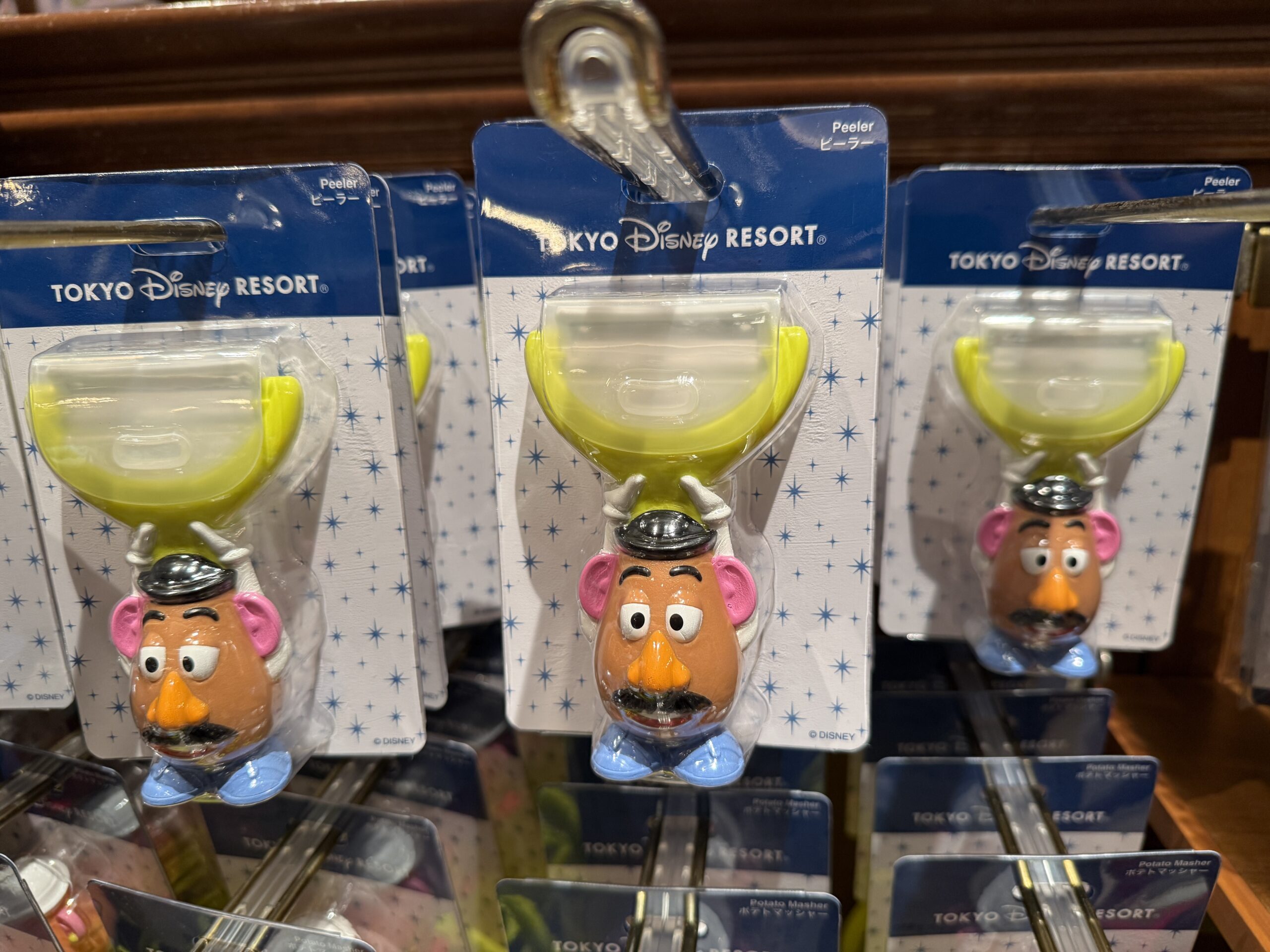 This potato peeler is shaped like Mr. Potato Head. The handle of the peeler is the character who is holding up the lime green peeler.