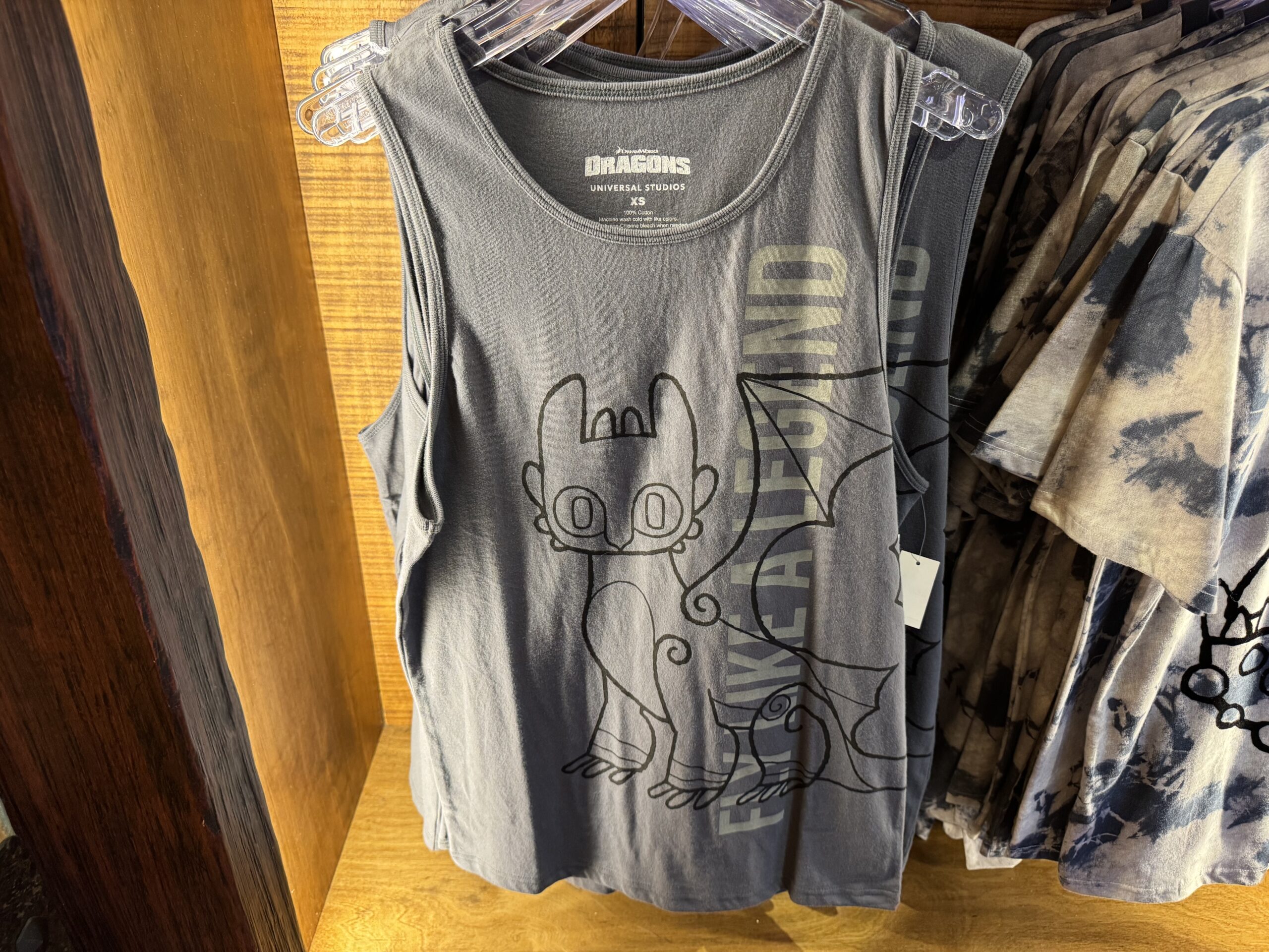The gray tank top has a lineart image of Toothless and "Fly like a legend" text running vertically on one side of the top.