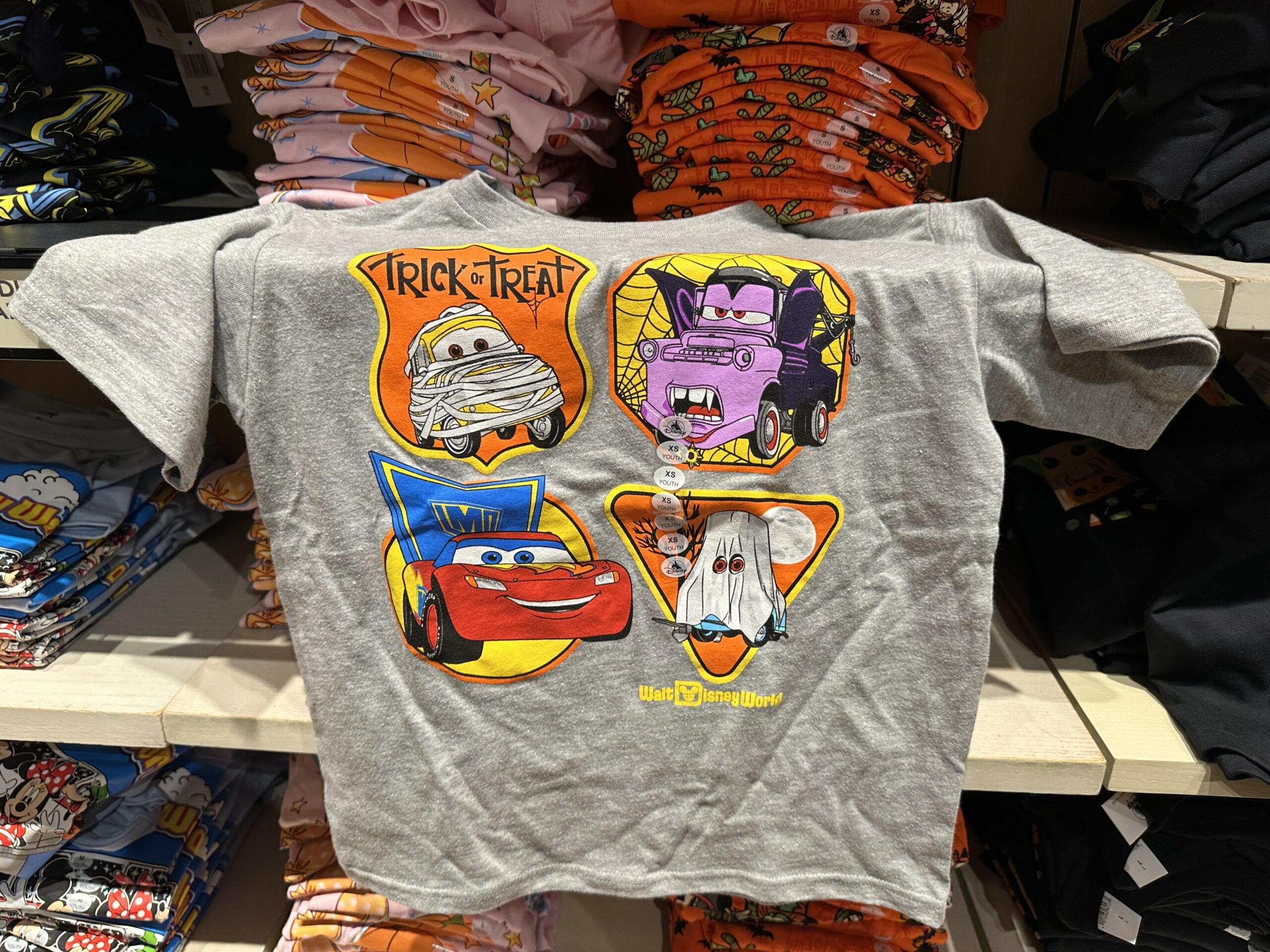 This gray tee has Cars characters dressed in Halloween costumes. Luigi is a mummy, Mater is a vampire, McQueen is a super hero, and Ramone is a ghost.