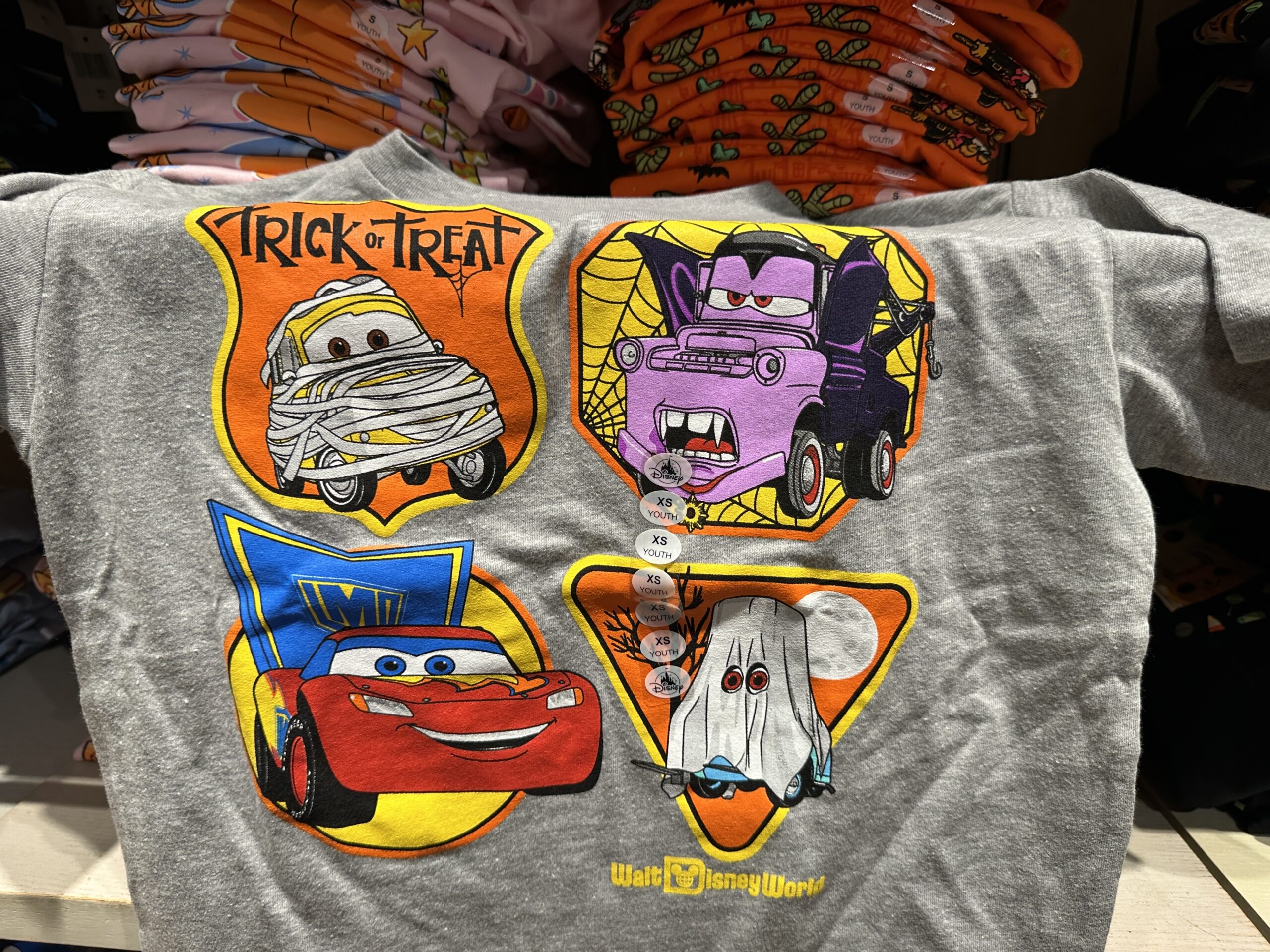 This gray tee has Cars characters dressed in Halloween costumes. Luigi is a mummy, Mater is a vampire, McQueen is a super hero, and Ramone is a ghost.