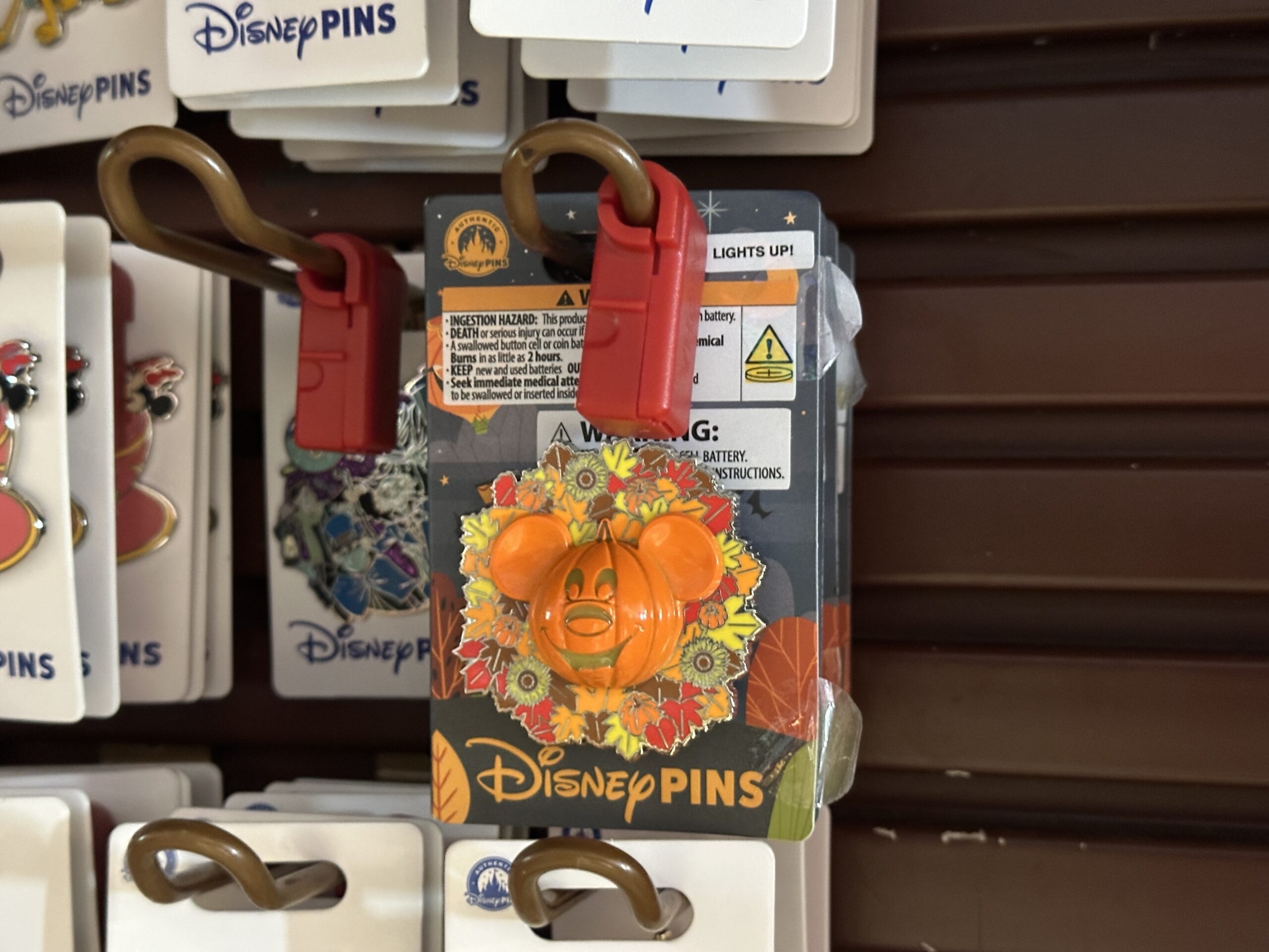 This pin is returning from last year. The Mickey jack-o'-lantern lights up, and a wreath of flowers, pumpkins, and leaves surround it.