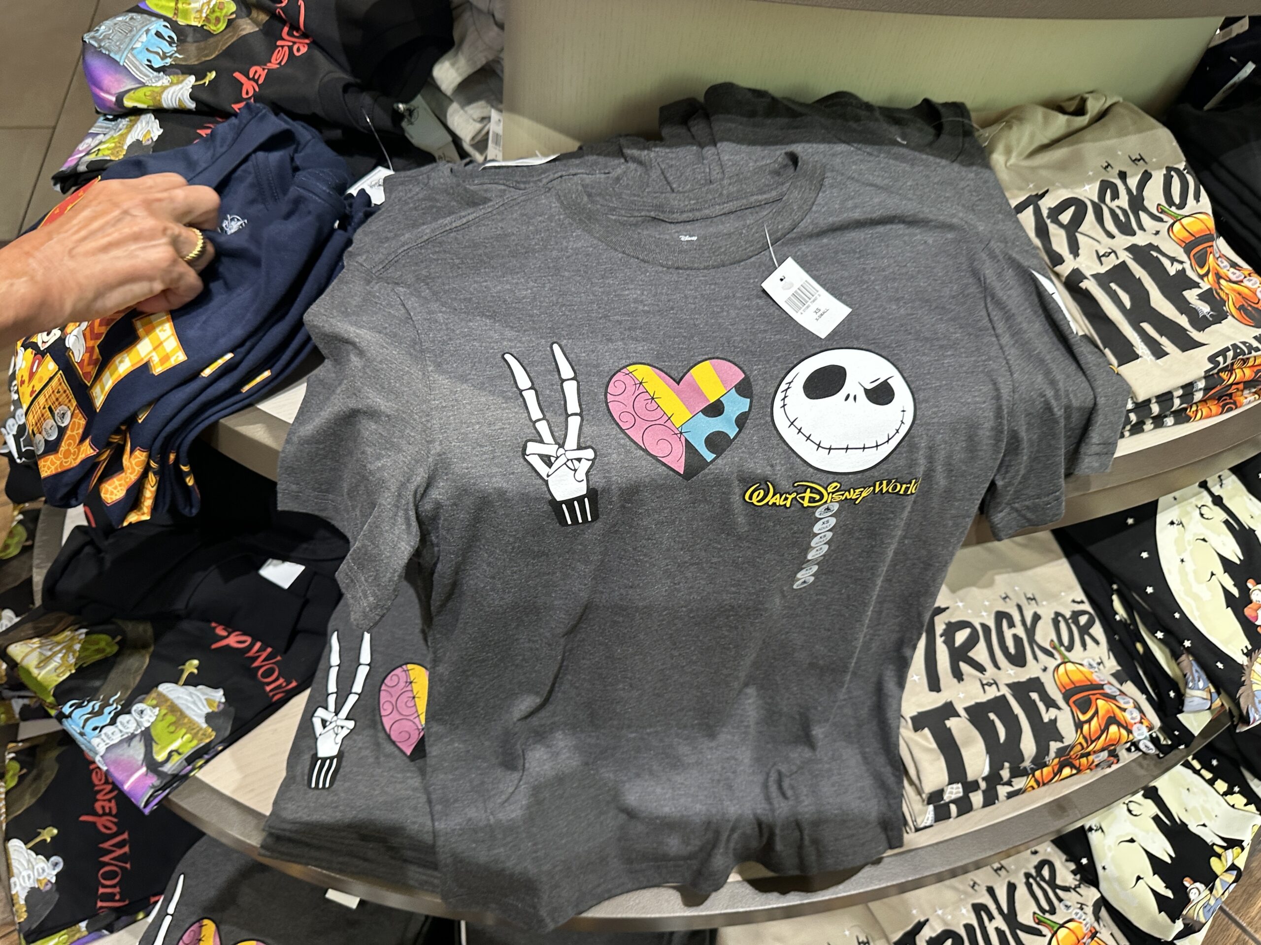 This gray shirt symbolizes peace, love, and Jack Skellington. Jack's fingers make the peace sign, the heart is filled with a Sally-inspired pattern, and Jack's face is on the end.