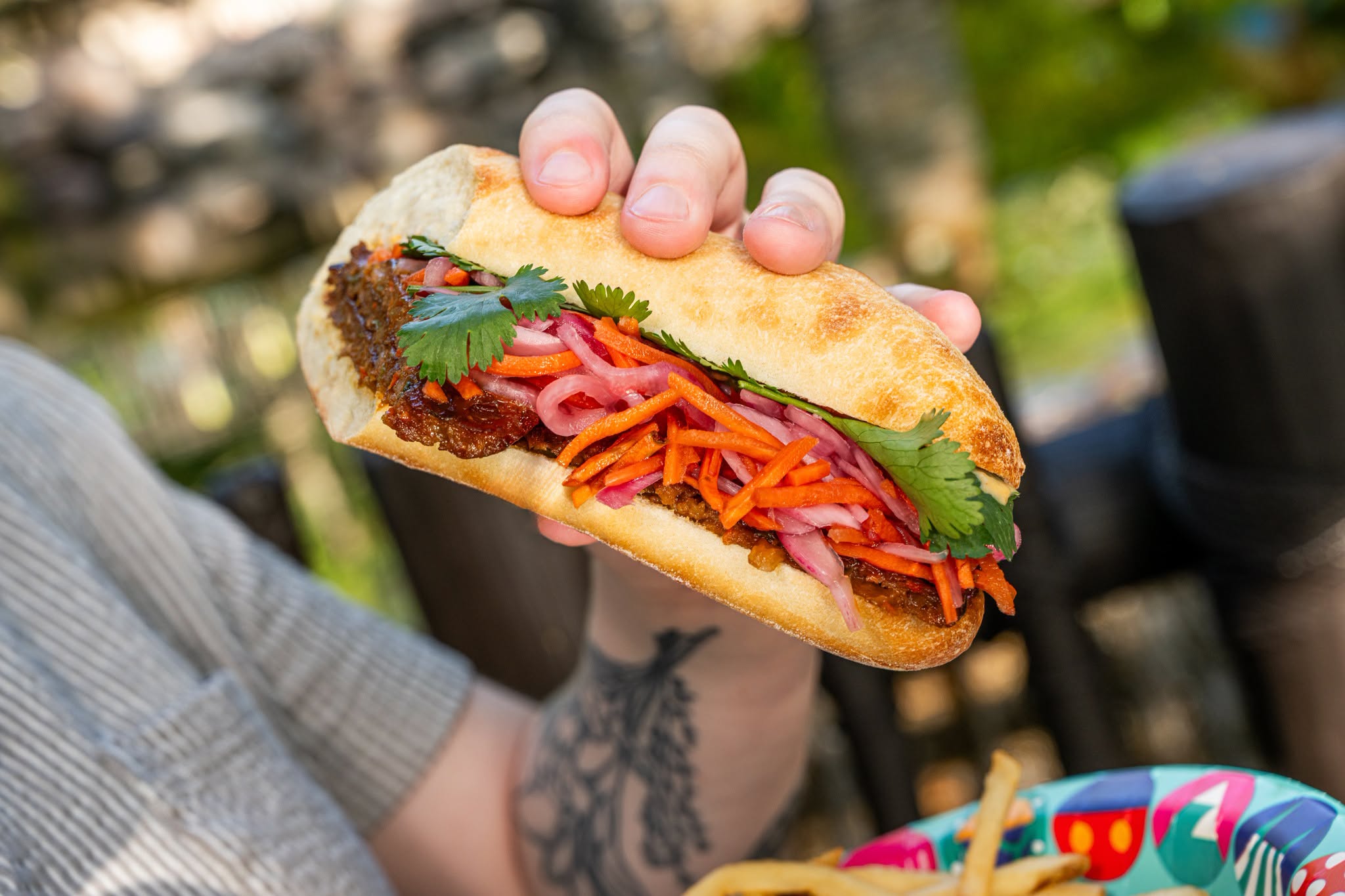 Korean Barbecue Sandwich for $12.49: Featuring Impossible Beef with Pickled Vegetables, Gochujang Mayonnaise, and Cilantro served on a Sourdough Baguette with French Fries.