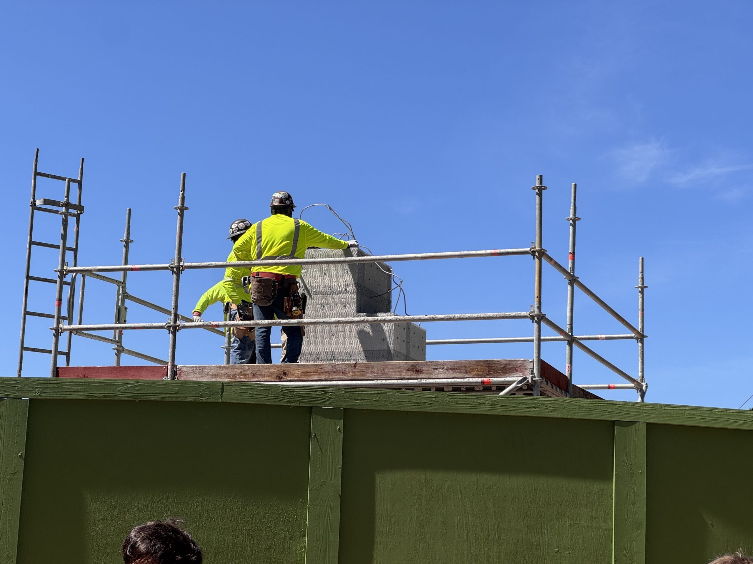 A few hours after our initial check on Thursday, we saw crew members had added rebar to the top of one of the entrance columns. The rebar is twisted to create the future shape of the additional concrete.