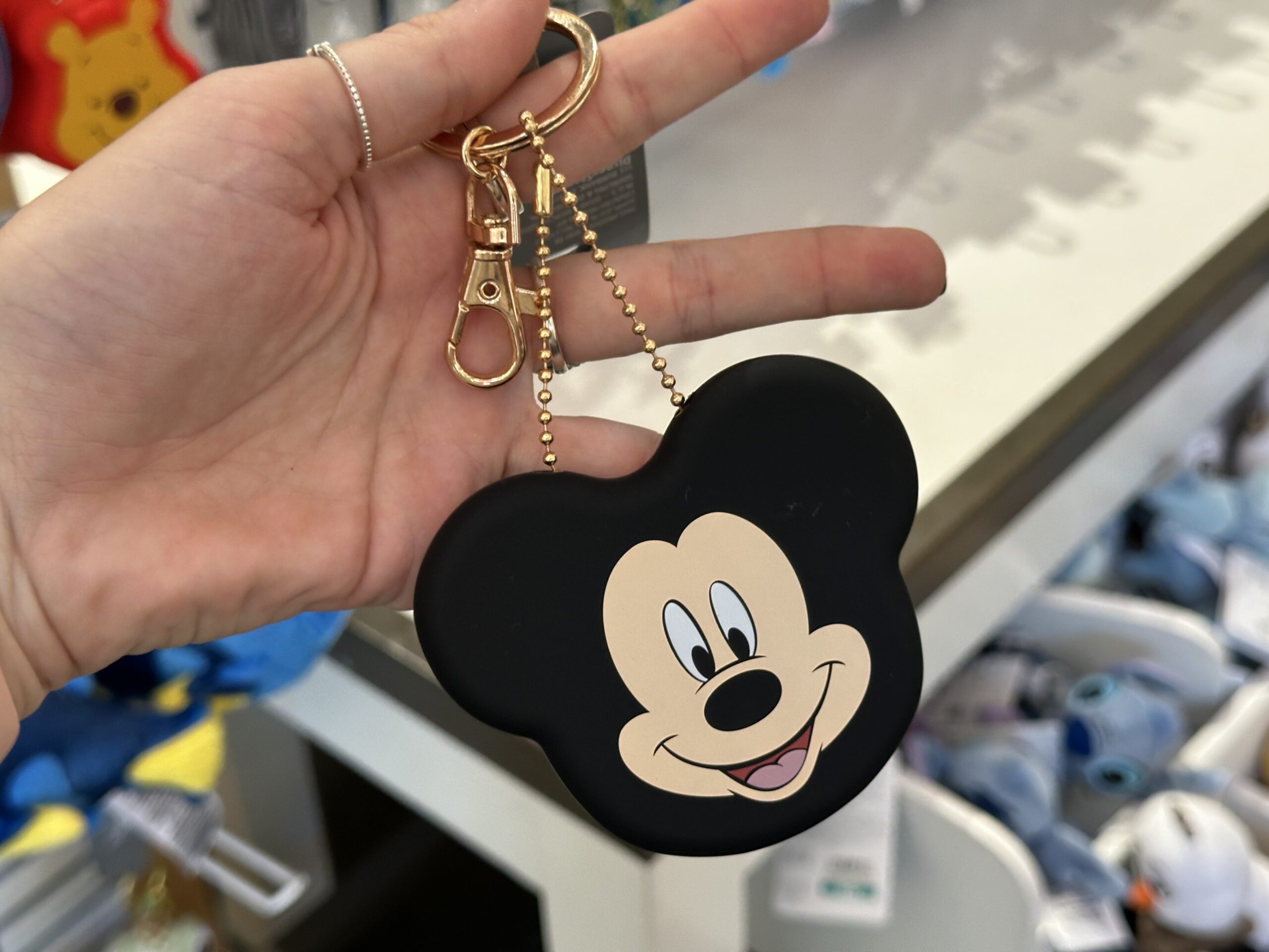 The black coin purse is in the shape of Mickey’s head with just the front of his face printed on the front. The shape of the coin purse represents his ears. This coin purse also has a rose gold-toned chain, lobster claw, and keyring.