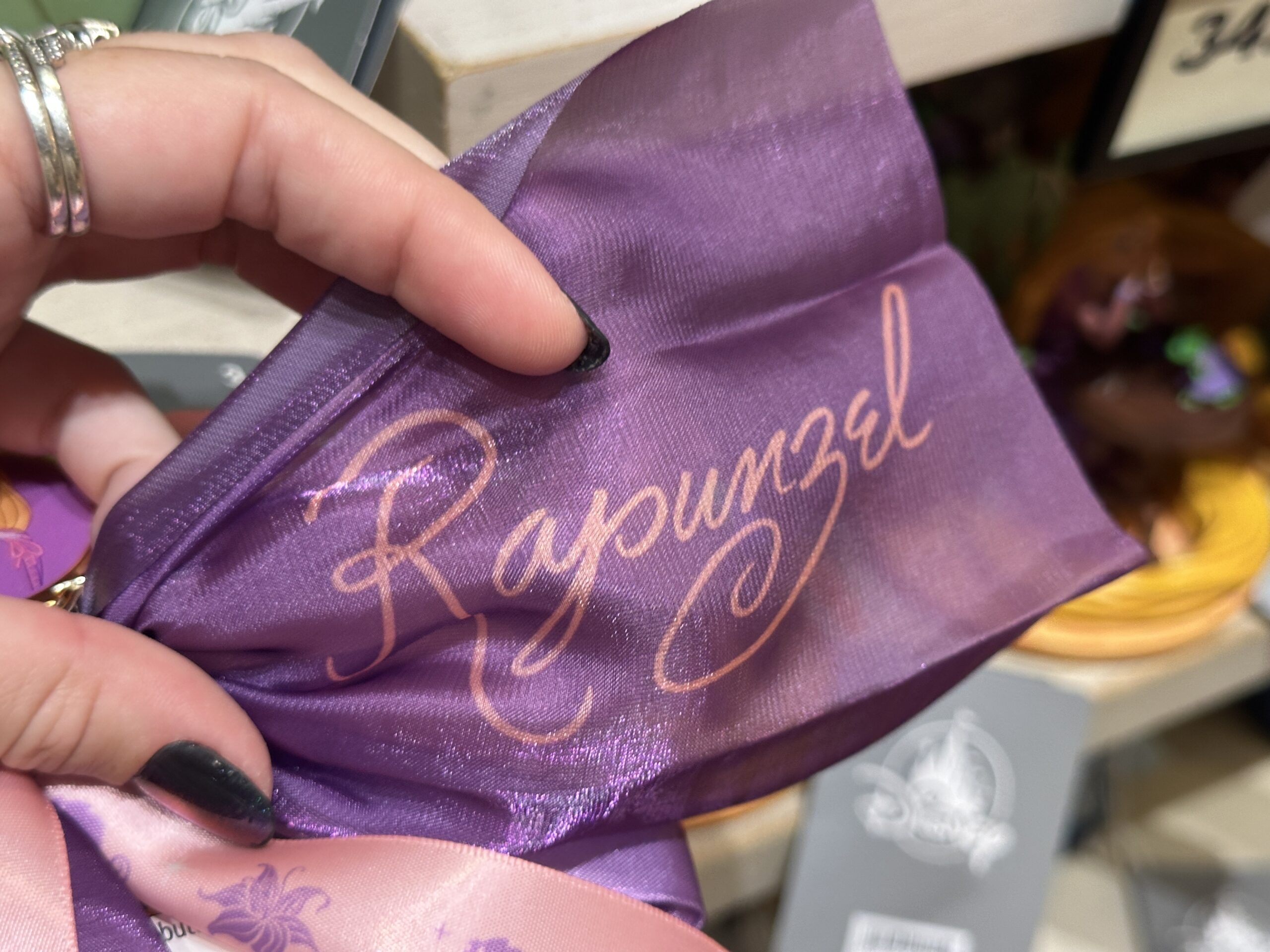 Pascal and the Sundrop flower decorate the pink tails, while Rapunzel's signature is printed in pink on one purple tail.