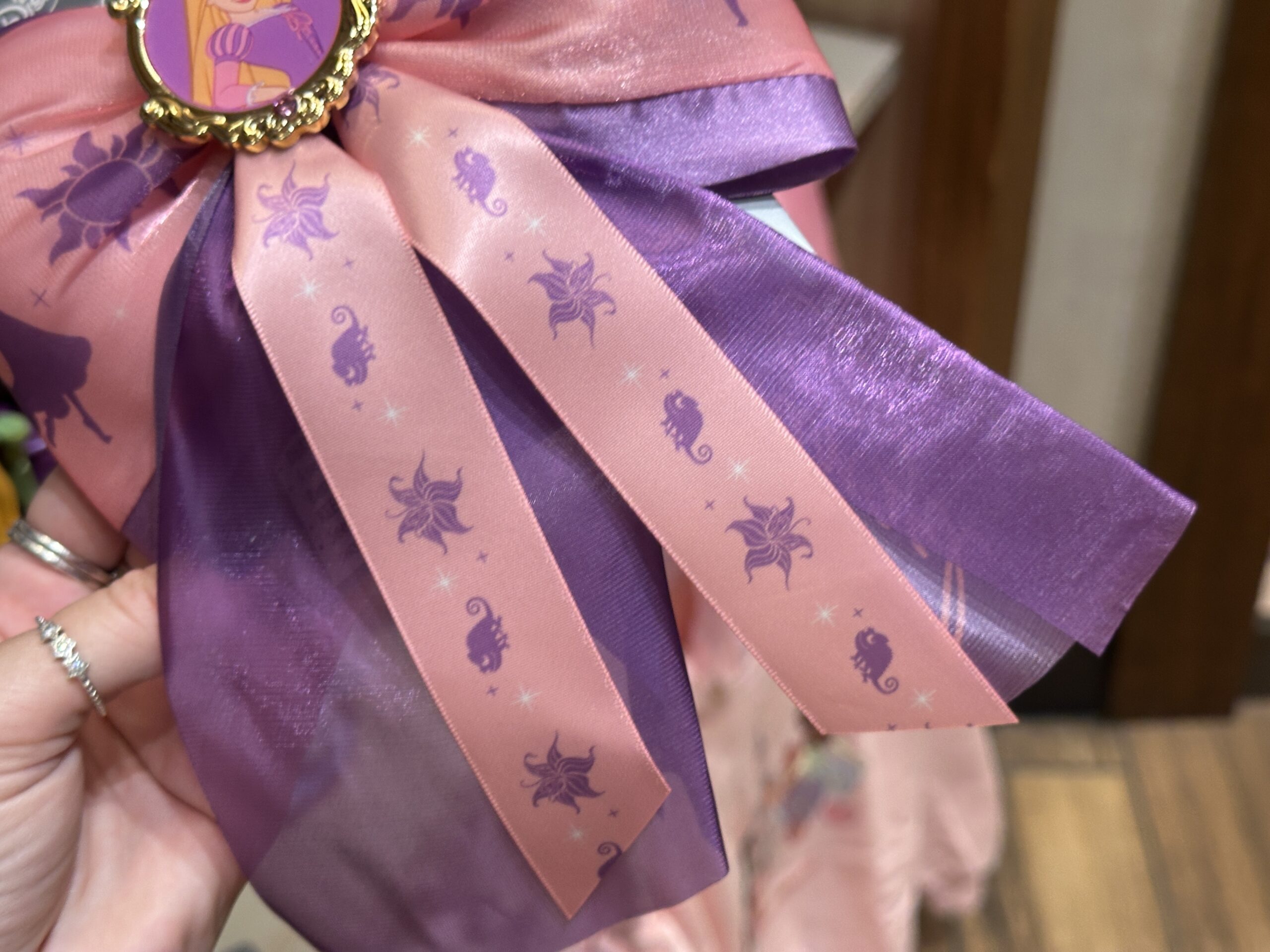 Pascal and the Sundrop flower decorate the pink tails, while Rapunzel's signature is printed in pink on one purple tail.