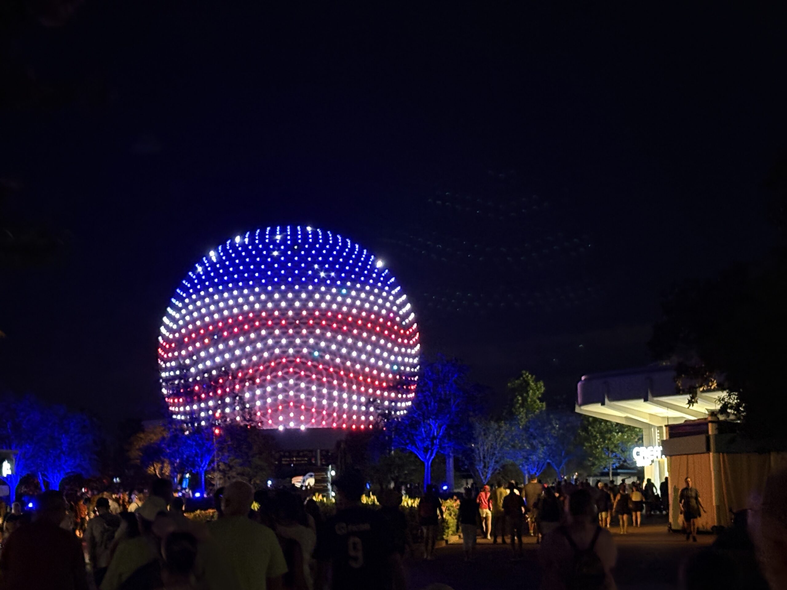 EPCOT has some patriotic lighting in place for America's 250th birthday this year. Spaceship Earth is decorated like an American flag, and other facades have red, white, and blue lighting.