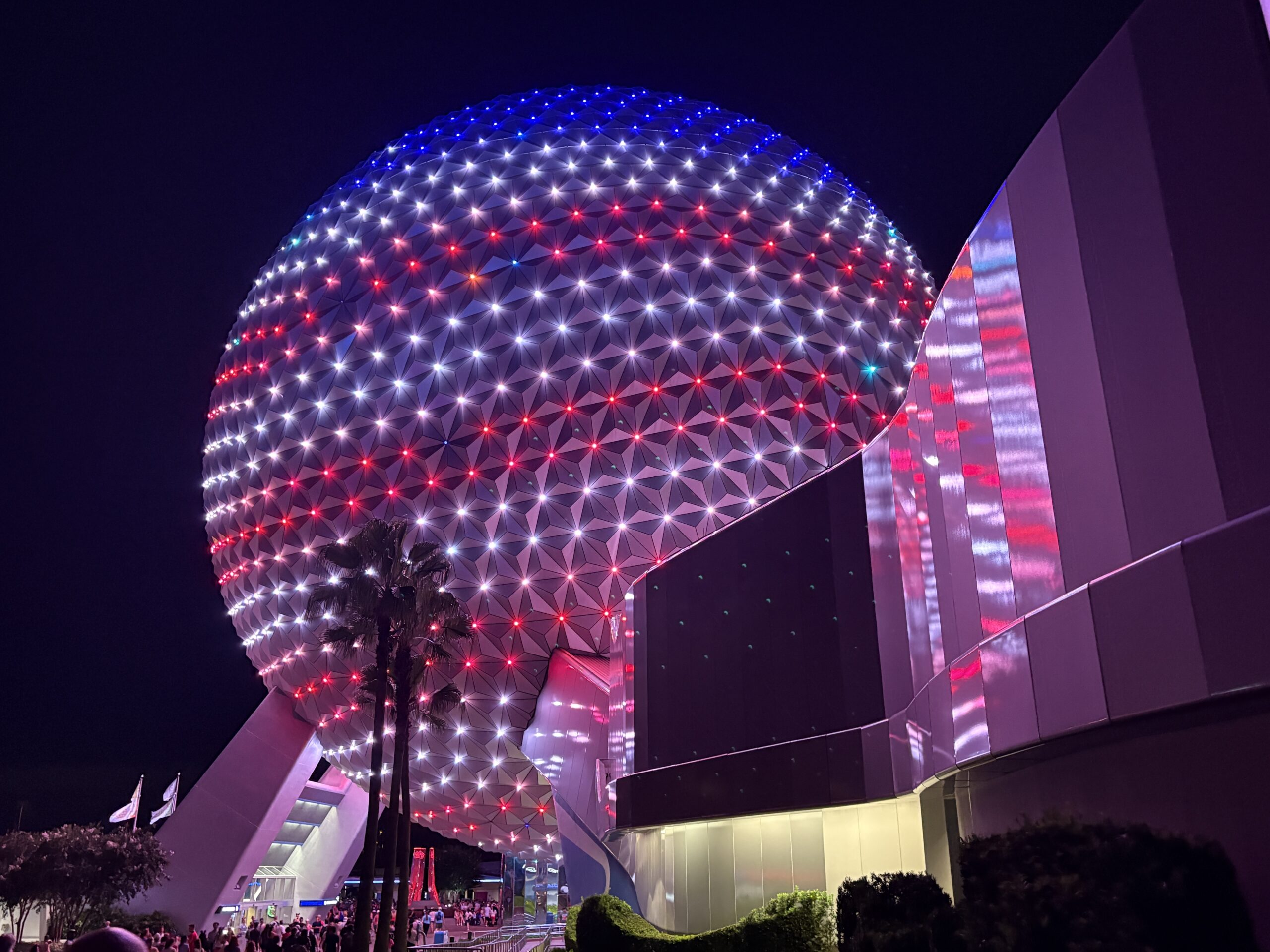 EPCOT has some patriotic lighting in place for America's 250th birthday this year. Spaceship Earth is decorated like an American flag, and other facades have red, white, and blue lighting.