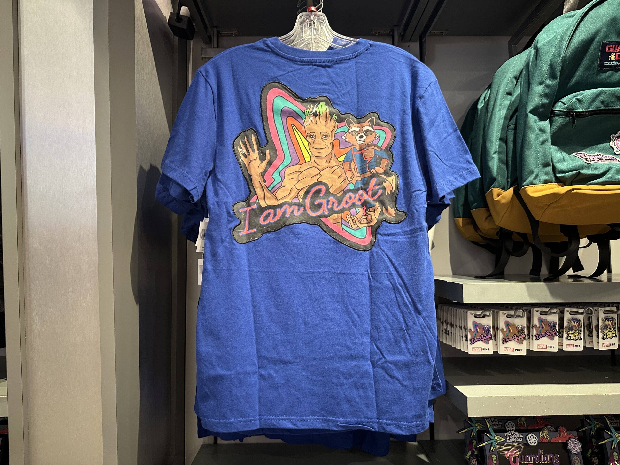 On the back is a rainbow Nova Corps logo behind images of Groot and Rocket. "I am Groot" is in pink script across the art.