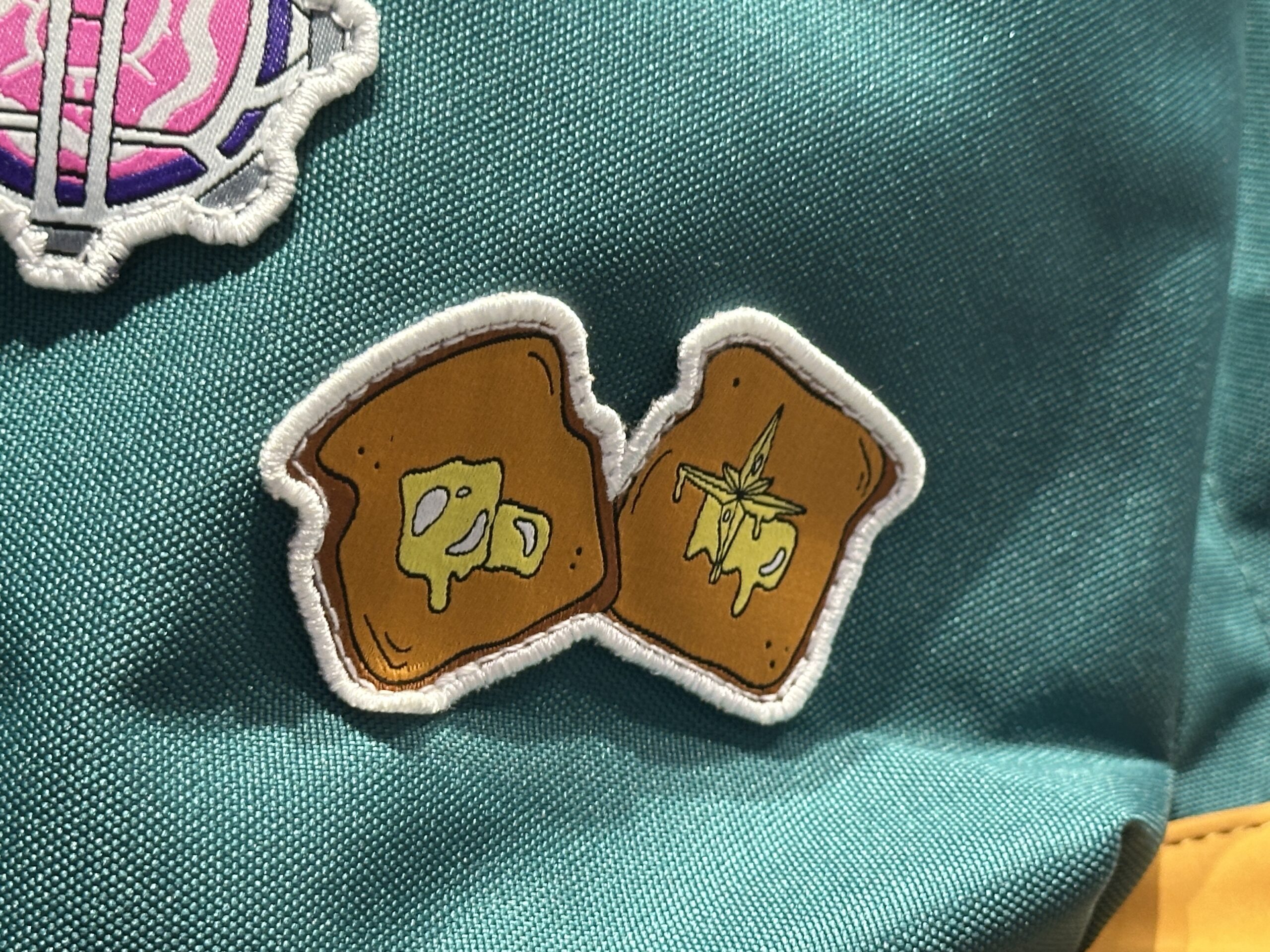 Patches on the front pocket depict toast with butter in the shape of the Nova Corps logo, the Cosmic Generator, and the same artwork from the purple sweatshirt.