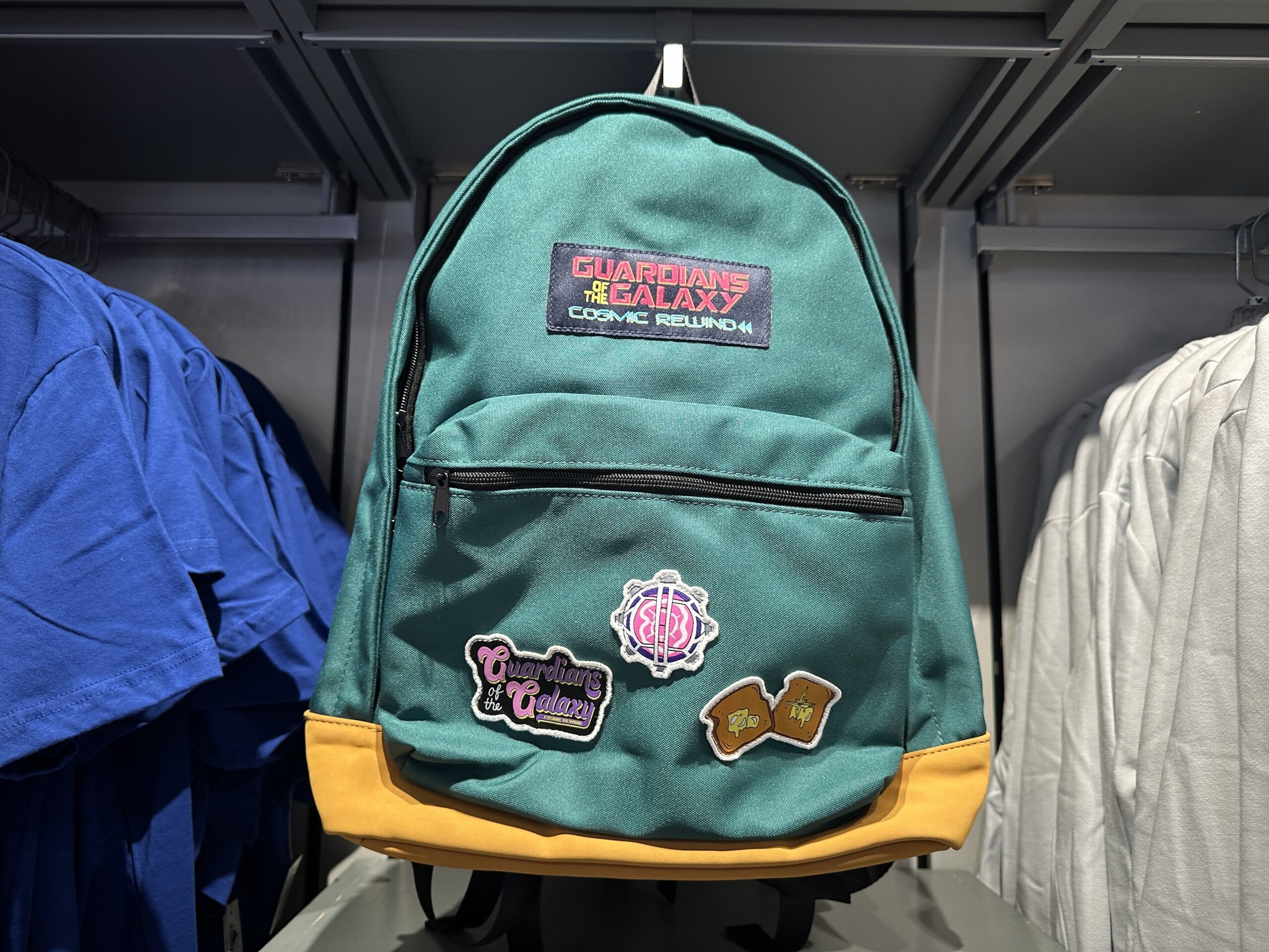 The green school-style backpack has a Guardians of the Galaxy: Cosmic Rewind patch above the front pocket. It has black zippers and a yellow base.