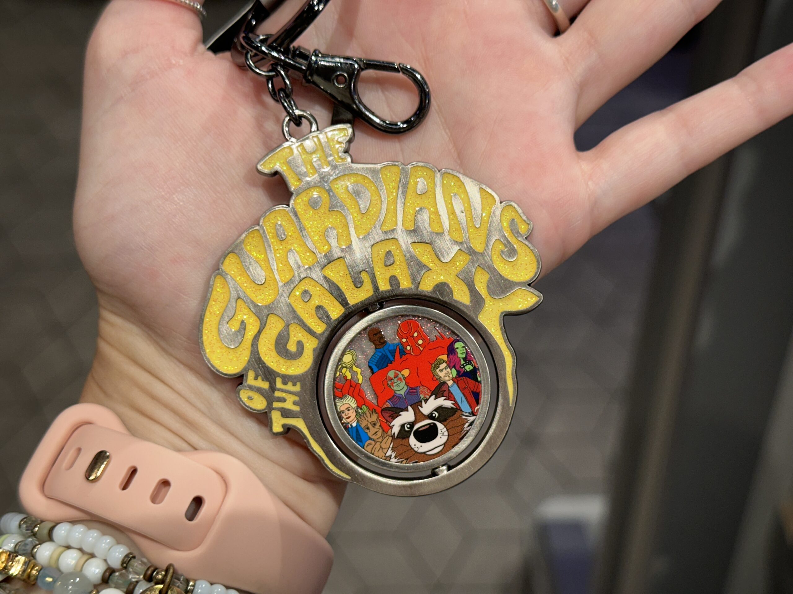 "The Guardians of the Galaxy" is in sparkly yellow lettering on this keychain. The spinning medallion reads "Cosmic Rewind" in pink on one side. On the reverse is art of the ride's characters.