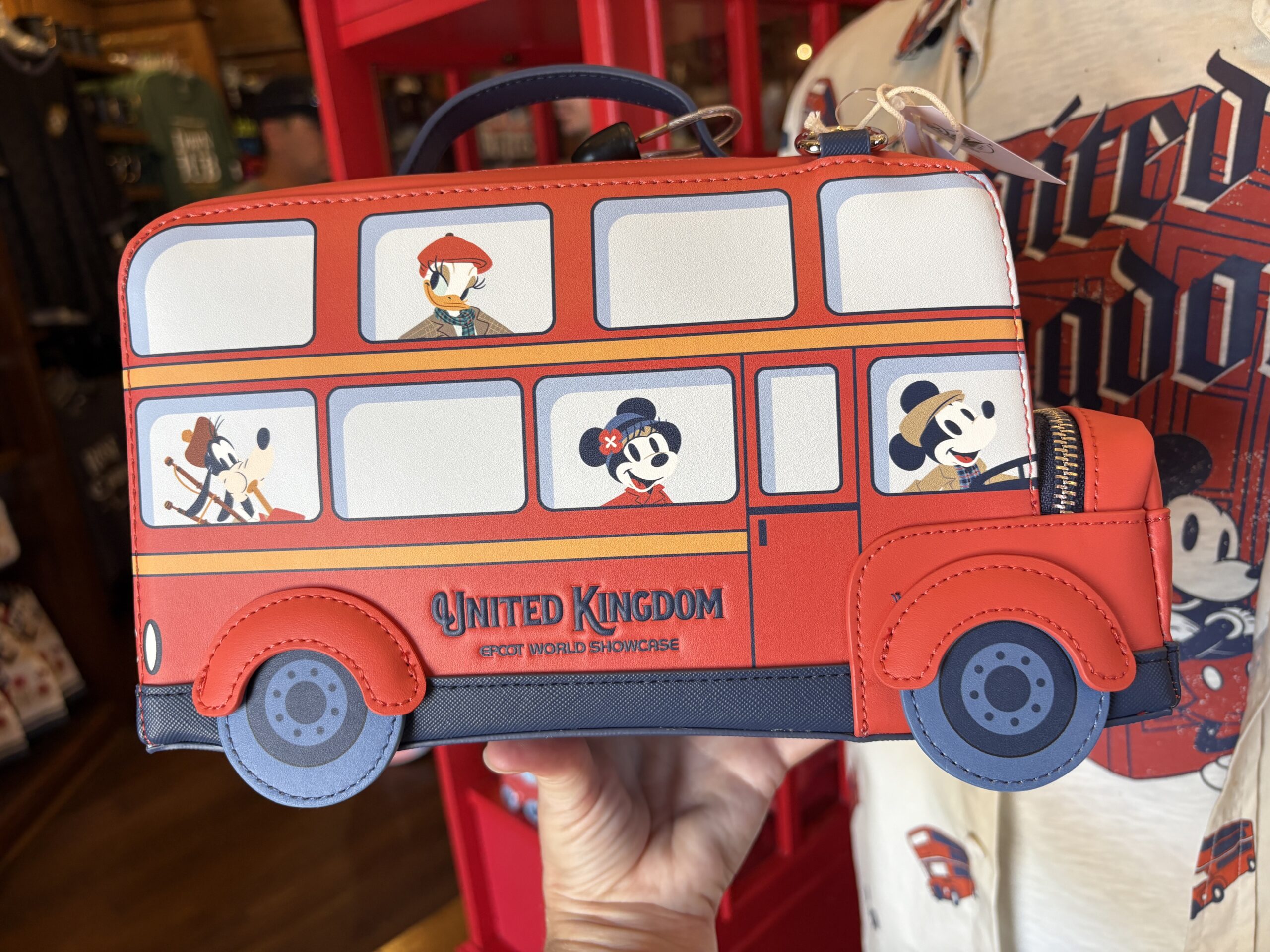 Donald, Scrooge McDuck, Goofy, Daisy, Minnie, and Chip 'n' dale are also pictured. They're all wearing U.K.-inspired accessories like Scrooge's Scottish-style hat and Goofy's bagpipes. "United Kingdom EPCOT World Showcase" is stamped in blue on each side.