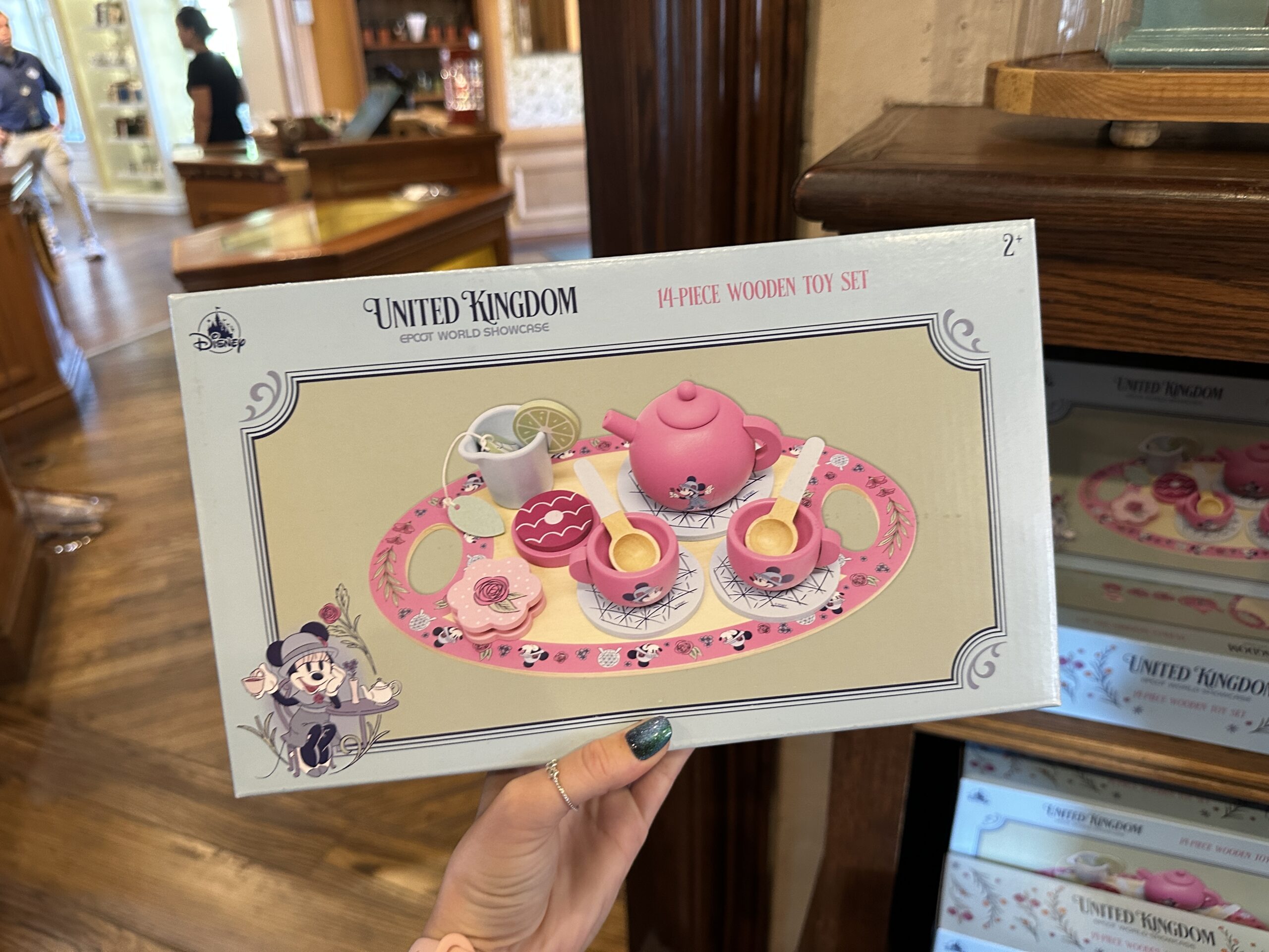 It includes one pink tea pot and two pink tea cups, all featuring Minnie; a pitcher; three Spaceship Earth coasters; two spoons; a fake lemon slice, which fits on the pitcher; a fake tea bag; two fake cookies; and a tray.