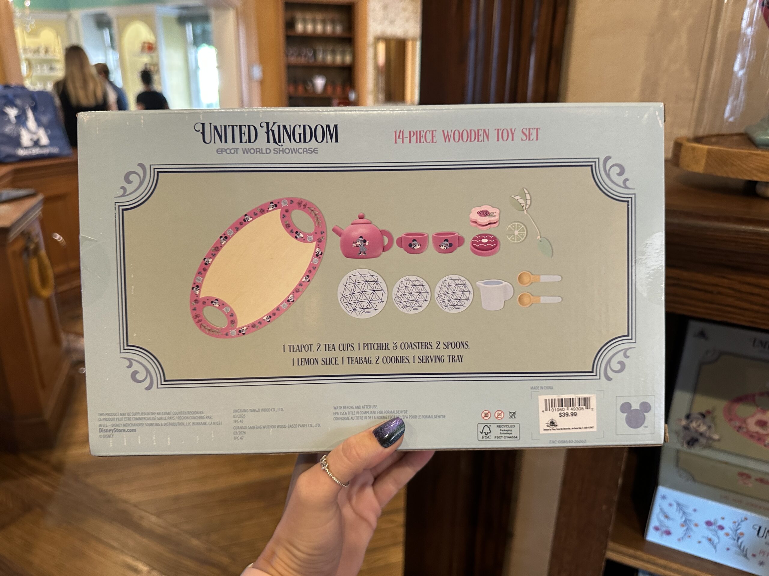 It includes one pink tea pot and two pink tea cups, all featuring Minnie; a pitcher; three Spaceship Earth coasters; two spoons; a fake lemon slice, which fits on the pitcher; a fake tea bag; two fake cookies; and a tray.