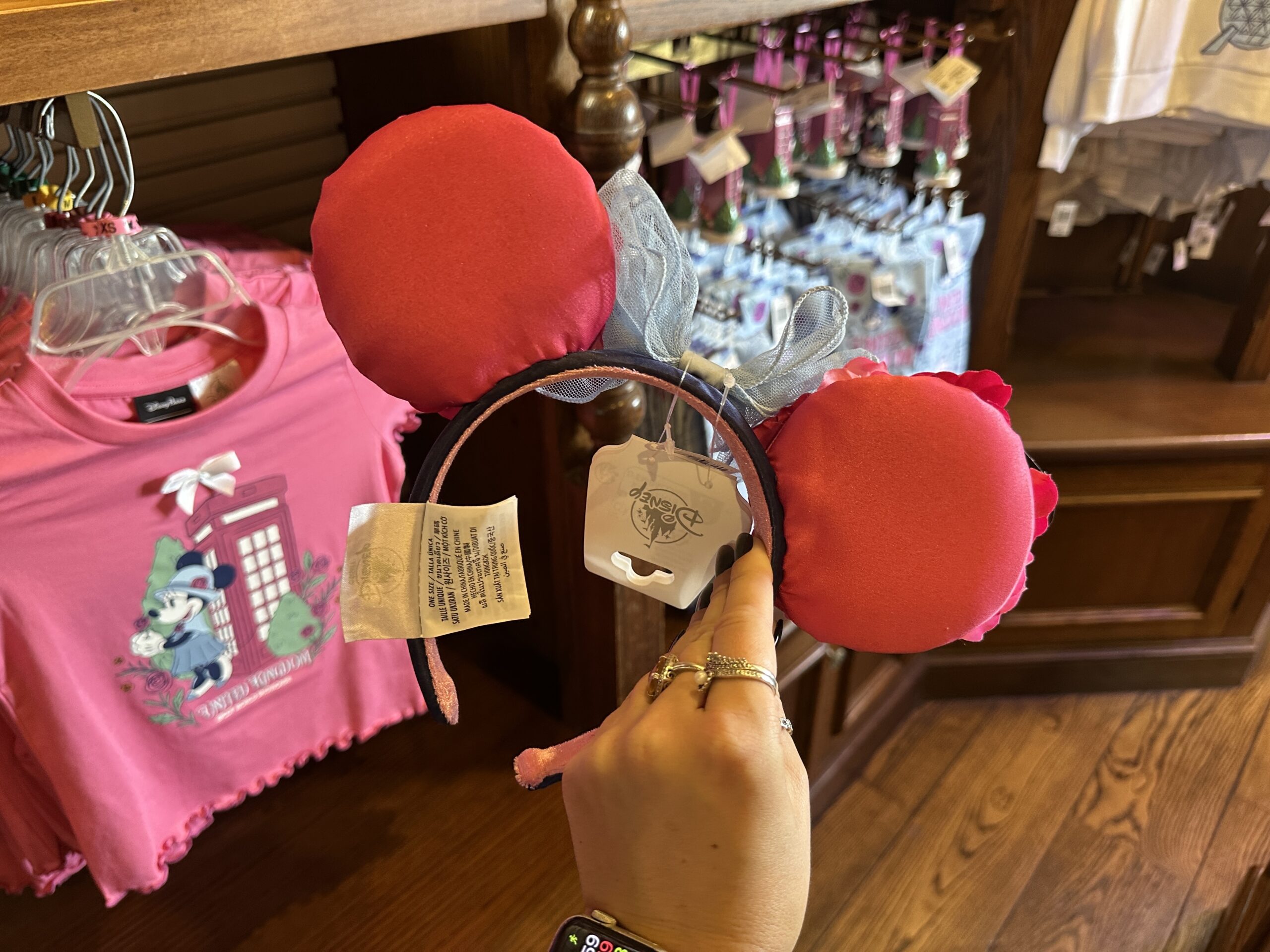 The backs of the ears are solid pink satin. The exterior of the headband is black with "United Kingdom EPCOT World Showcase" on one side. The lining is pink velour.