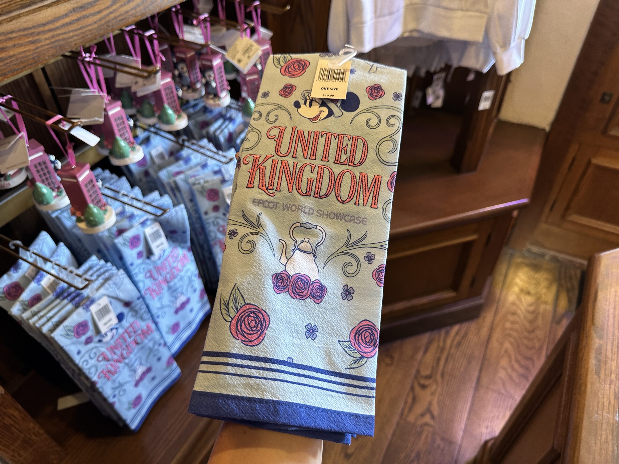 "United Kingdom" is embroidered in pink lettering on this pale green towel. It has blue trim and stripes along the edge.