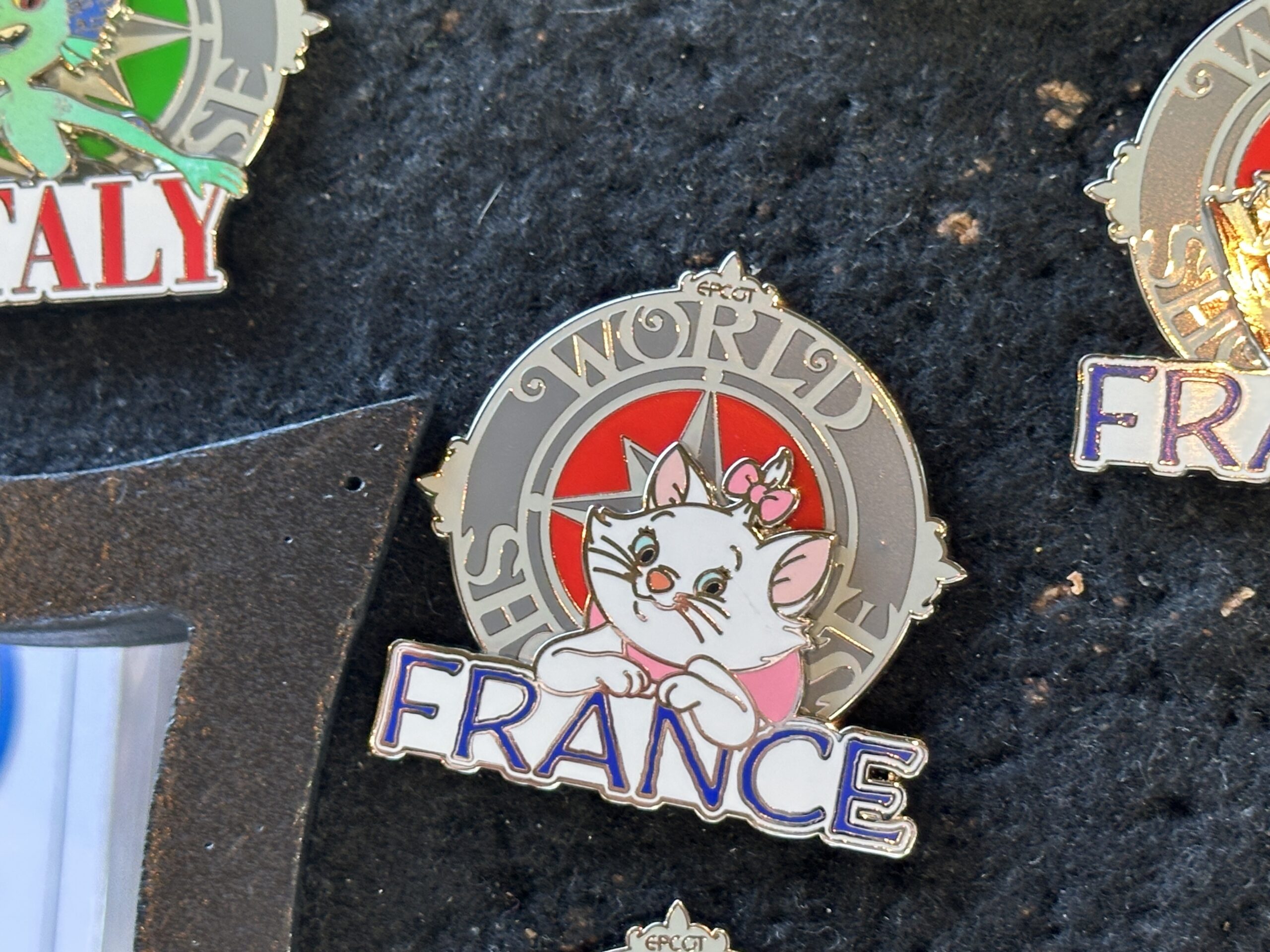 One of three France pins features Marie from The Aristocats. The backgrounds of these pins are red while "France" is in blue.
