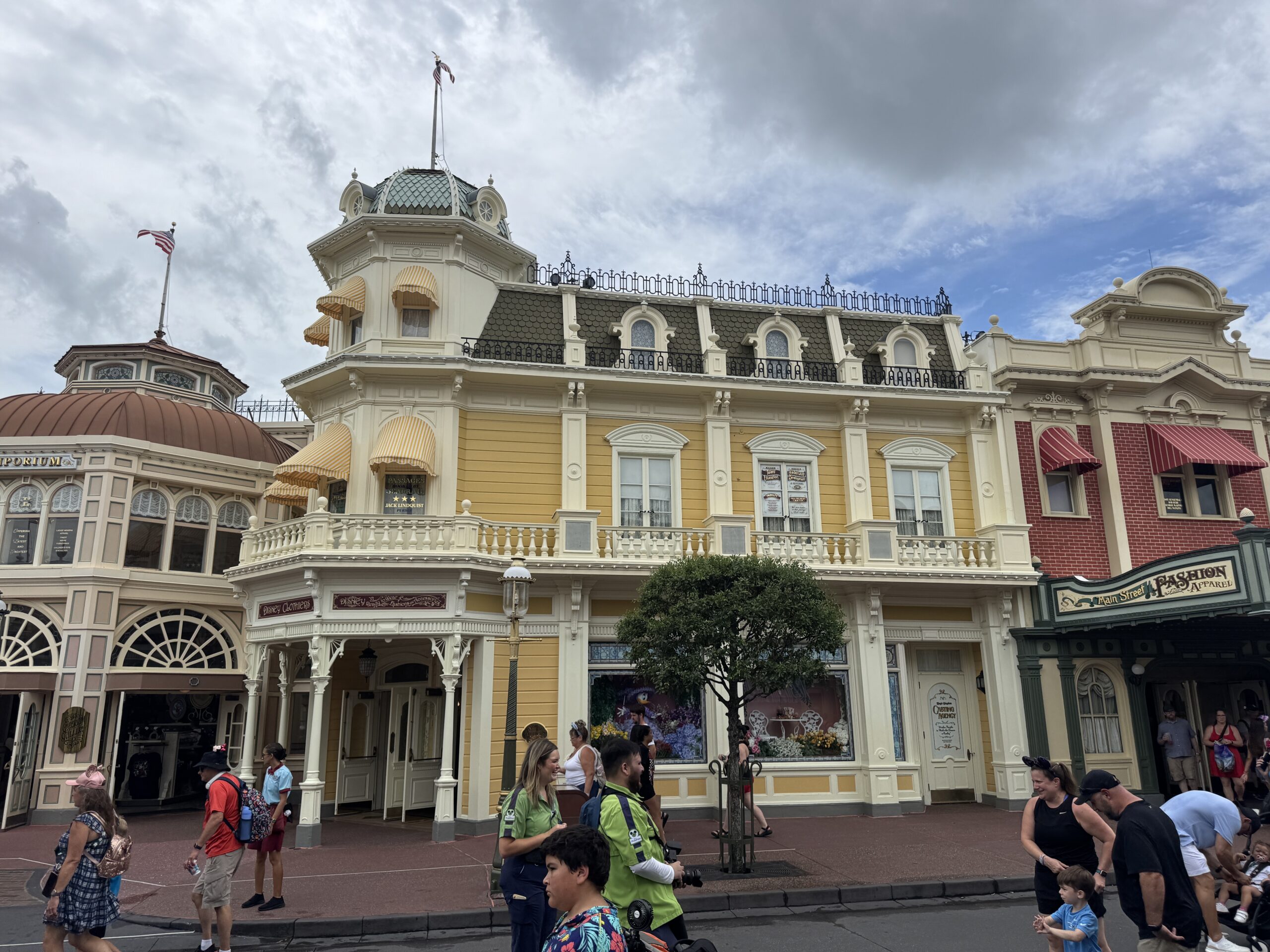 Emporium shop at Magic Kingdom. The building is yellow with ornate white detailing and railings.