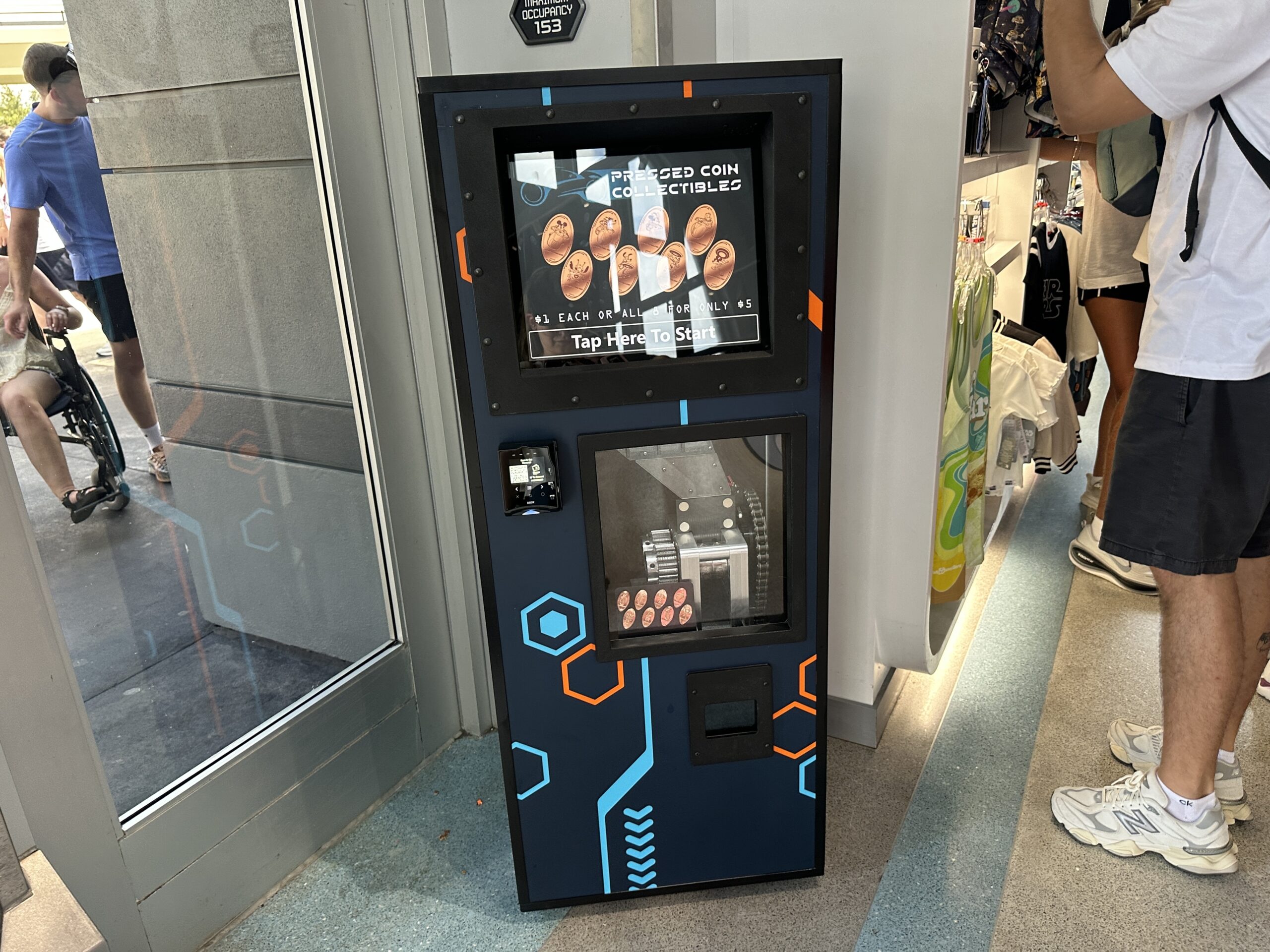 We spotted the new pressed penny machine in Tomorrowland Launch Depot in Magic Kingdom. This shop is near TRON Lightcycle Run, so the aesthetic of the machine is similar to that of the ride and the film.