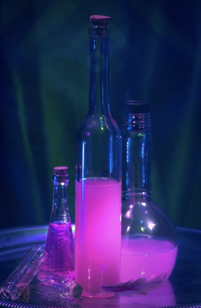 The caption reads, "A mysterious potion is brewing… 🧪💜And the villain behind it has big plans for Oogie Boogie Bash. Any guesses who's concocting trouble this Halloween season?"