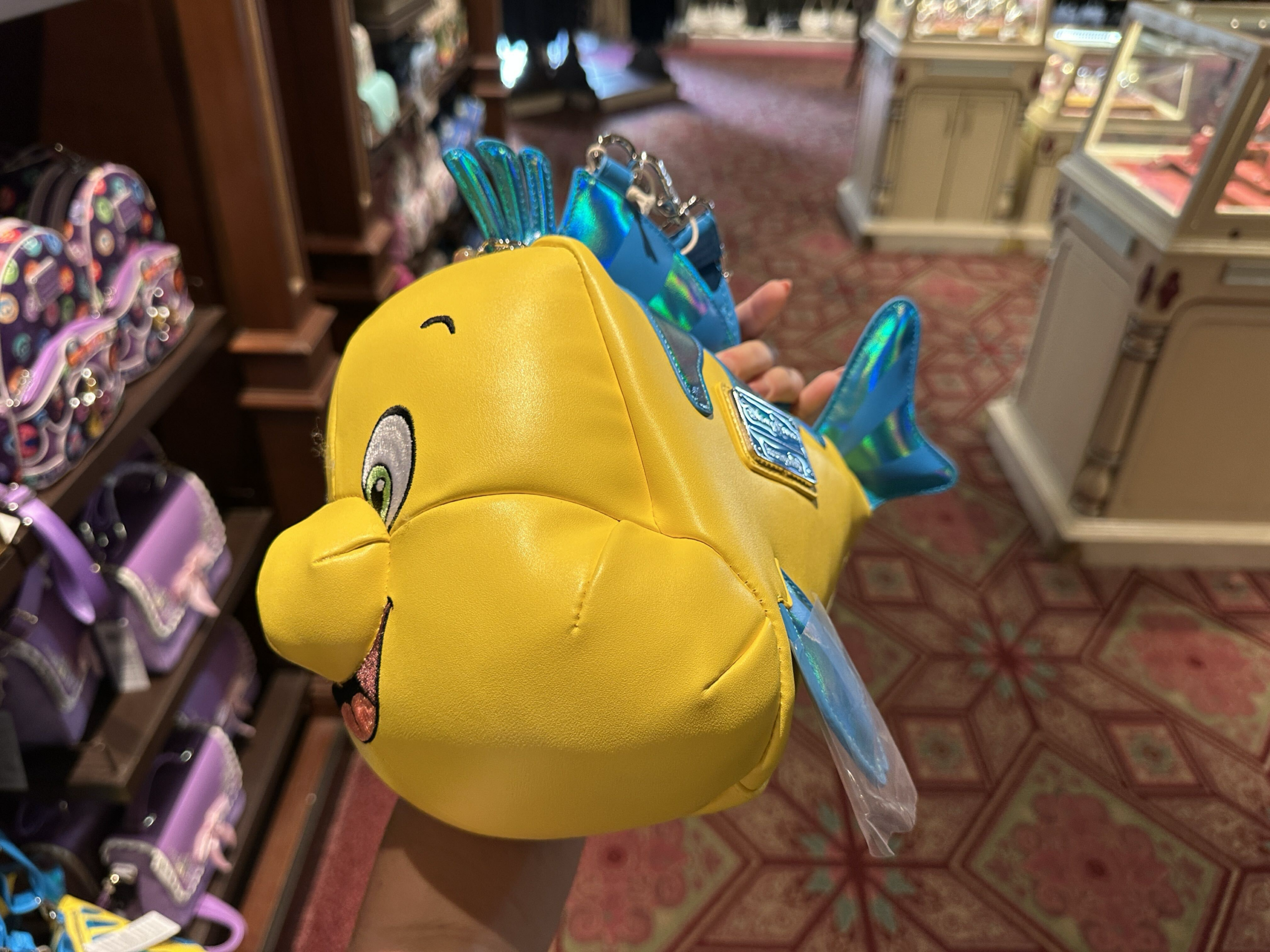 A new Flounder crossbody bag has swam into Magic Kingdom.