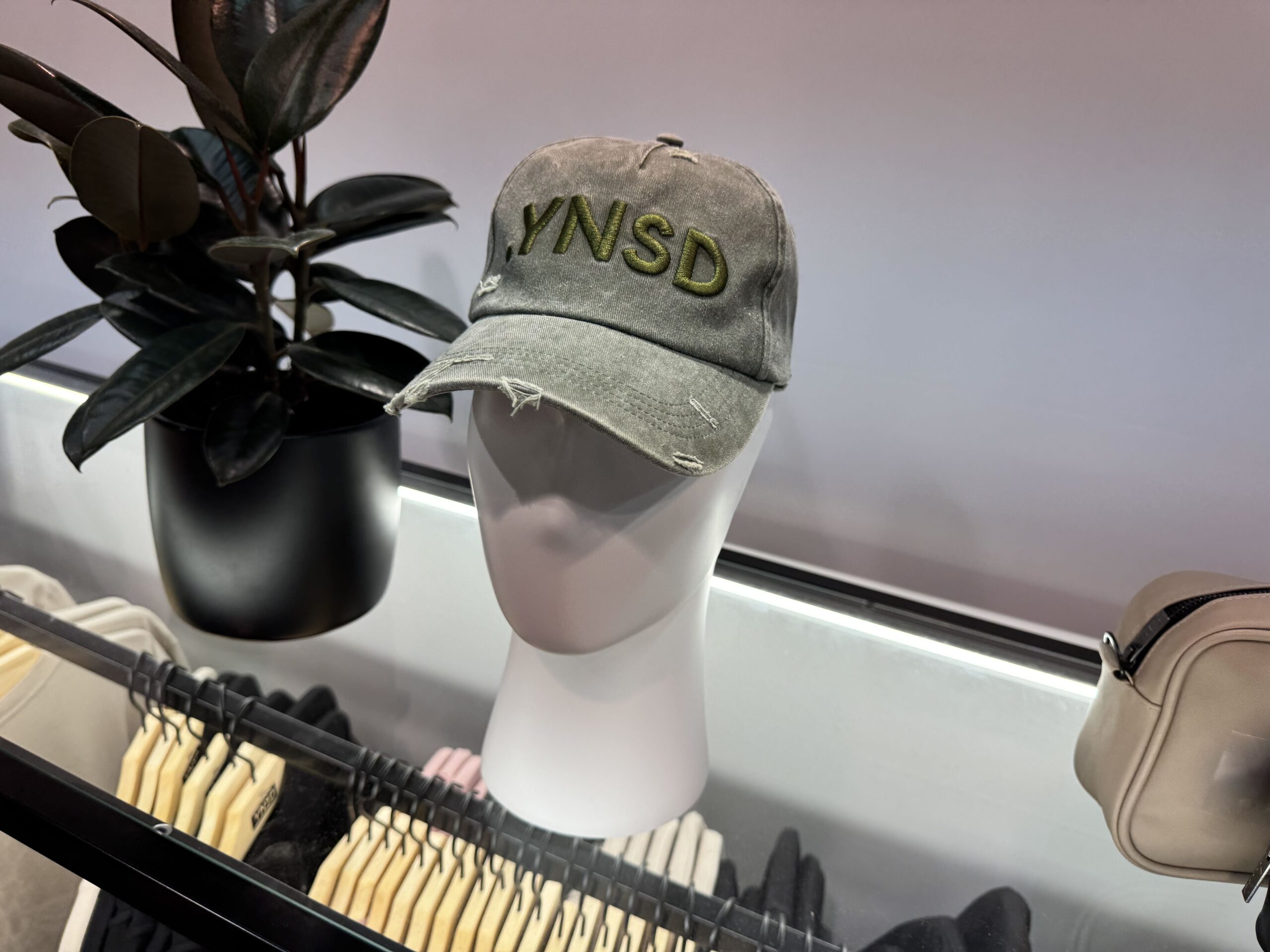 A distressed olive cap has the .YNSD logo embroidered on the front.