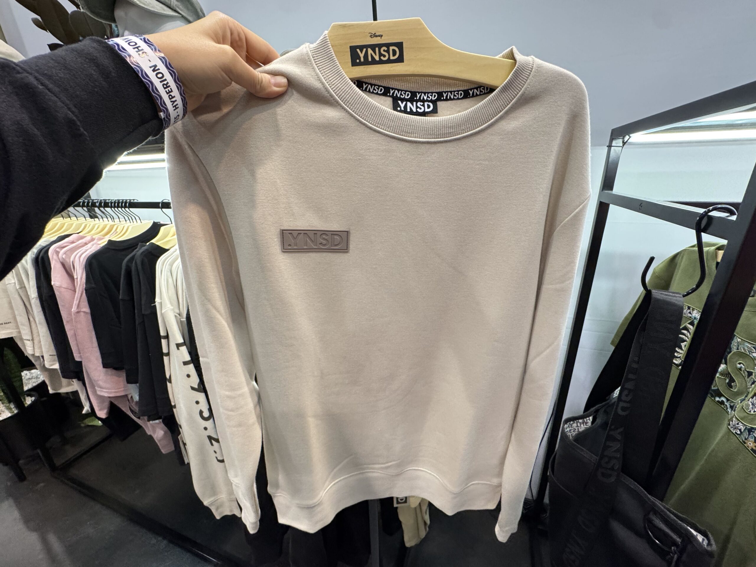 A cream colored crewneck is part of the collection. It has the brand patch on the chest, and [1.9.5.2.] on the sleeve. 1952 is the year Walt Disney Imagineering was established.