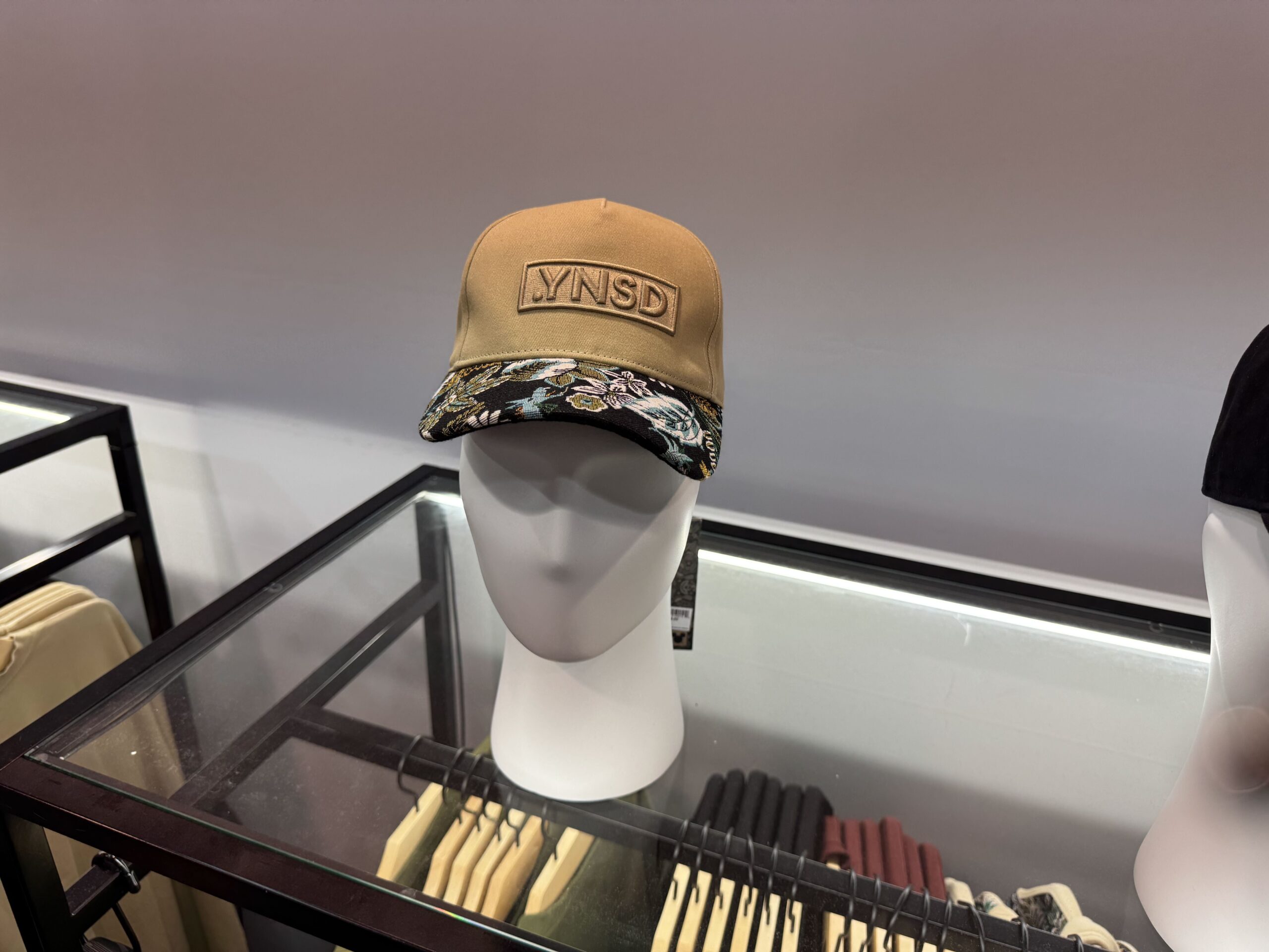 This dark tan-colored baseball cap has the .YNSD logo patch on the front, and the Haunted Mansion parlor carpet print on the brim.
