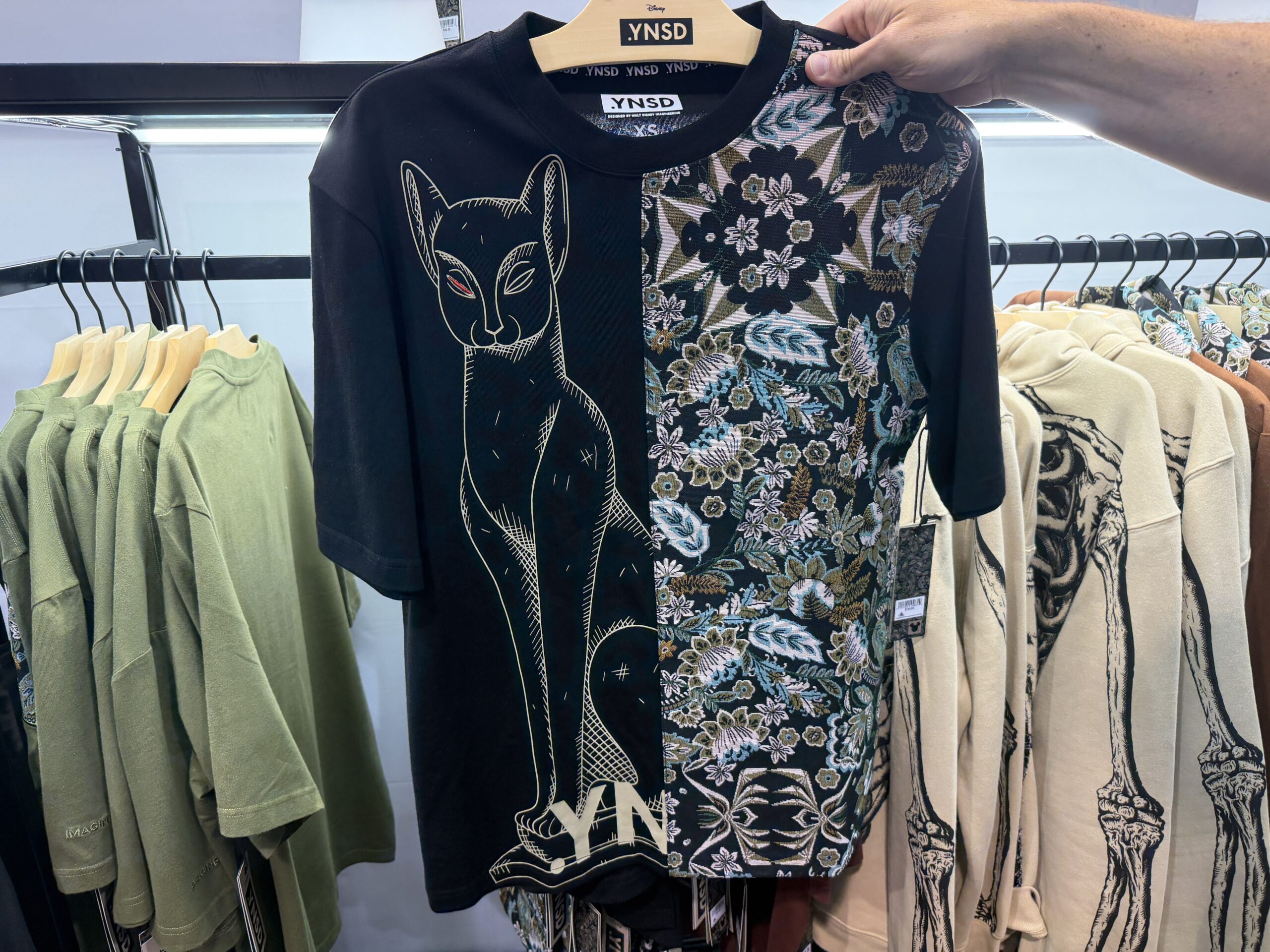 One side of the black tee has the parlor carpet print, and the other has the one-eyed cat.