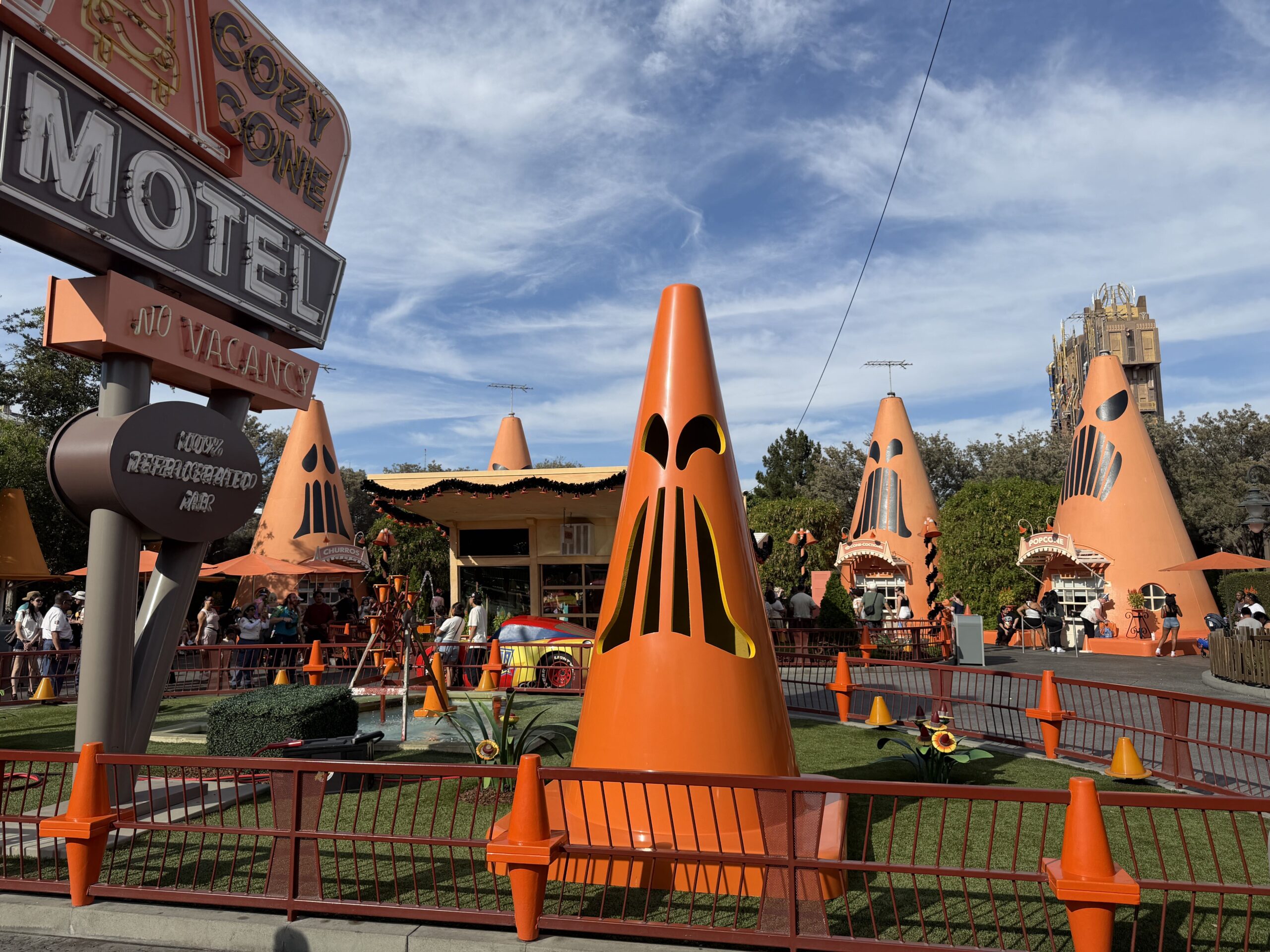 Giant Traffic cones with Jack-O'-lantern faces stand guarding around the perimeter of the Cozy Cone Motel, grimacing at guests for a fright.