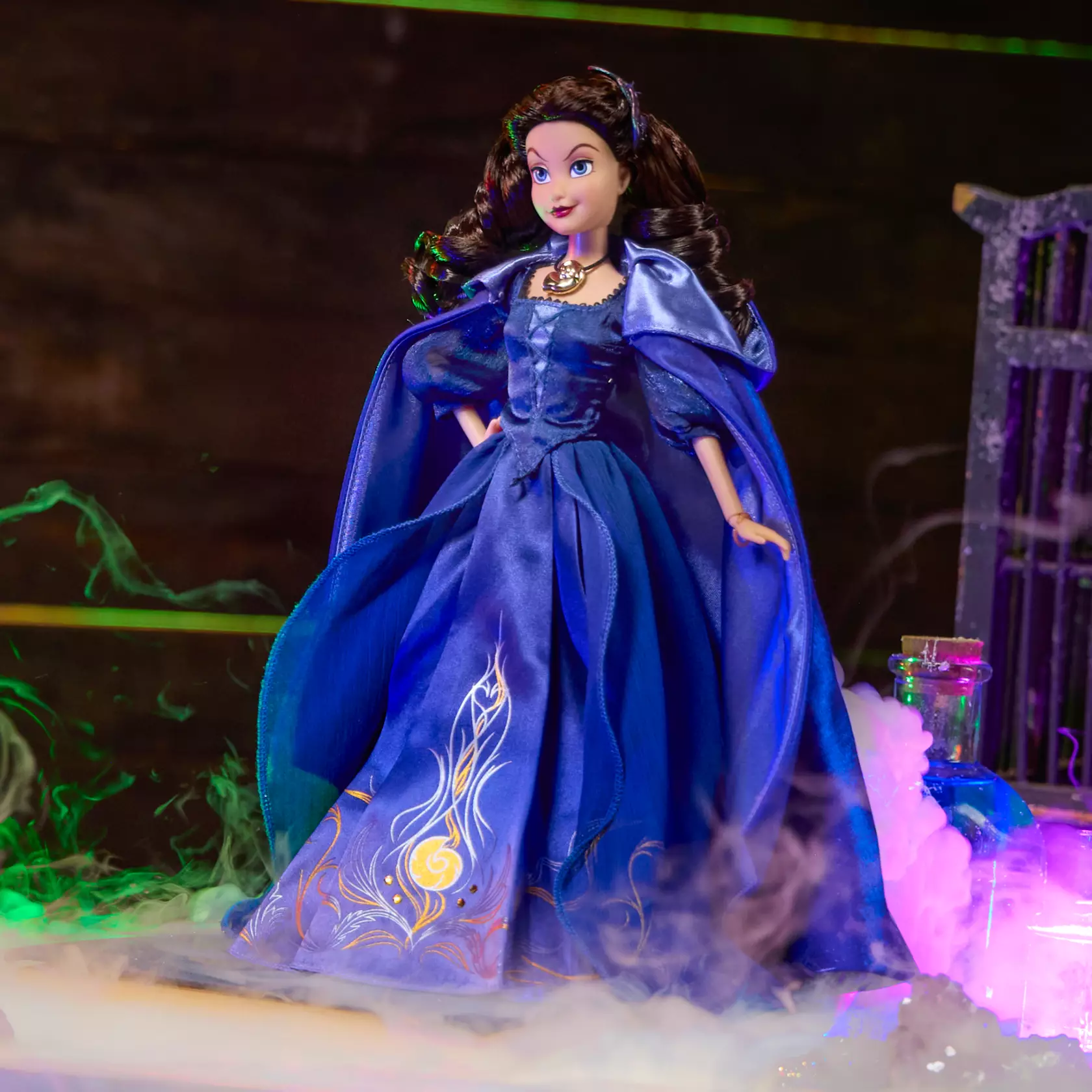 Disney Store's Autumn Special Edition 2026 doll is Vanessa, Ursula's alter ego. The 11 1/2" doll wears a purple satin gown and cape with picot trim at the neck, sheer organza puffed sleeves, and embroidered accents. Metallic foil filigree is printed on the skirt. She wears her golden nautilus shell necklace. It comes in window display packaging.