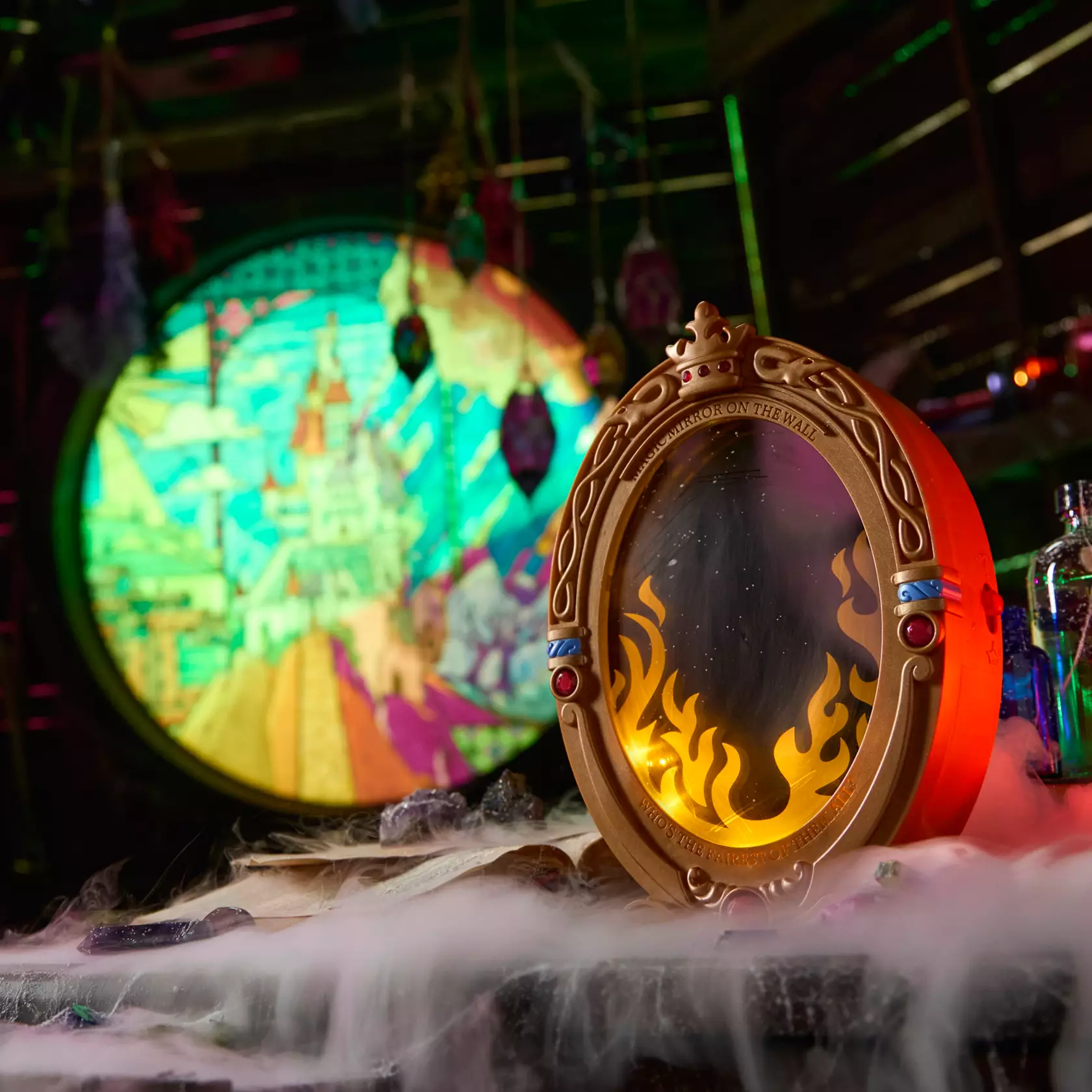 This plastic toy resembles the Magic Mirror with a sculpted 3D effect. Pressing the red jewel at the bottom of the frame activates lights and sounds. The Magic Mirror appears among light-up flames to speak to users.