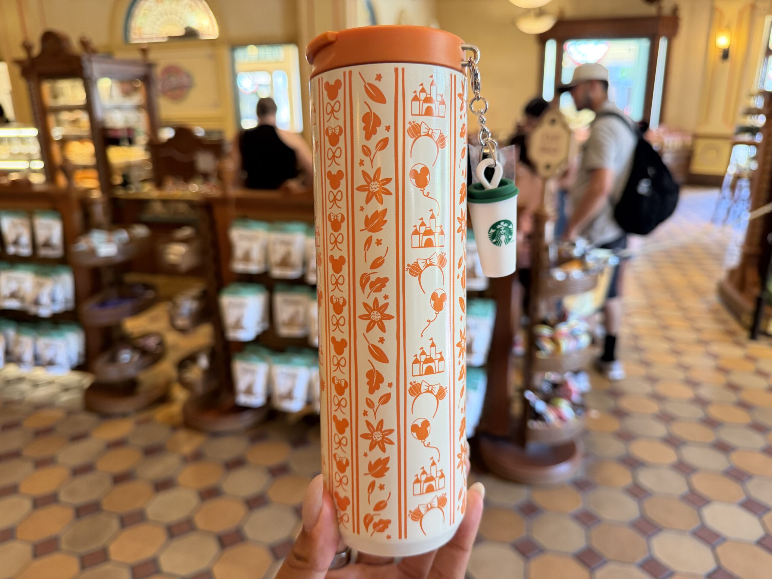 Other orange iconography includes Mickey and Minnie heads, small bows, Sleeping Beauty Castle, pumpkin ear headbands, and Mickey balloons.