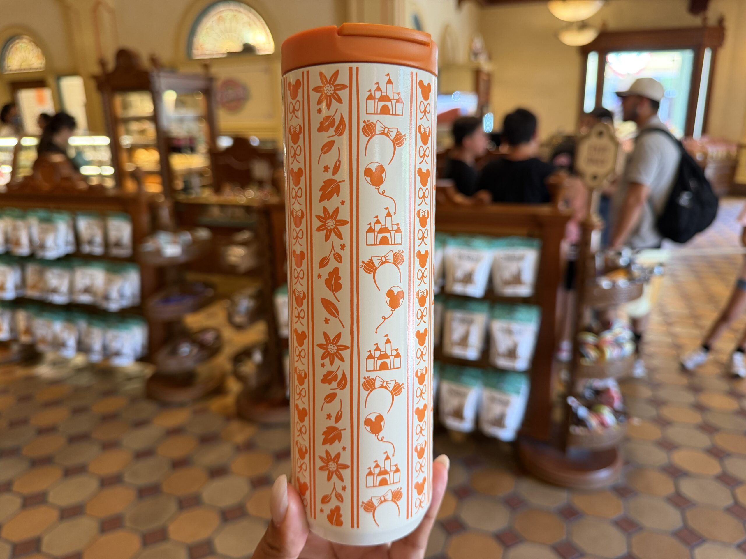 Other orange iconography includes Mickey and Minnie heads, small bows, Sleeping Beauty Castle, pumpkin ear headbands, and Mickey balloons.