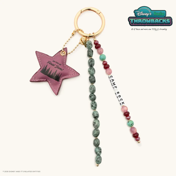 This bag charm comes with three items attached to a gold ring: A strand of red, pink, and aqua beads along with white letter blocks that spell out "CAMP ROCK"; a strand of black-speckled green stones; and a puffy fabric star that has black trees printed on it along with the text, "See you at final jam!"