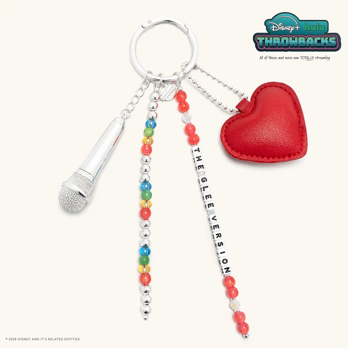 This bag charm comes with four items attached to a gold ring: A puffy red heart; a strand of red and white beads along with white letter blocks that spell out "THE GLEE VERSION"; a strand of silver, red, yellow, green, and blue round beads; and a small silver microphone.