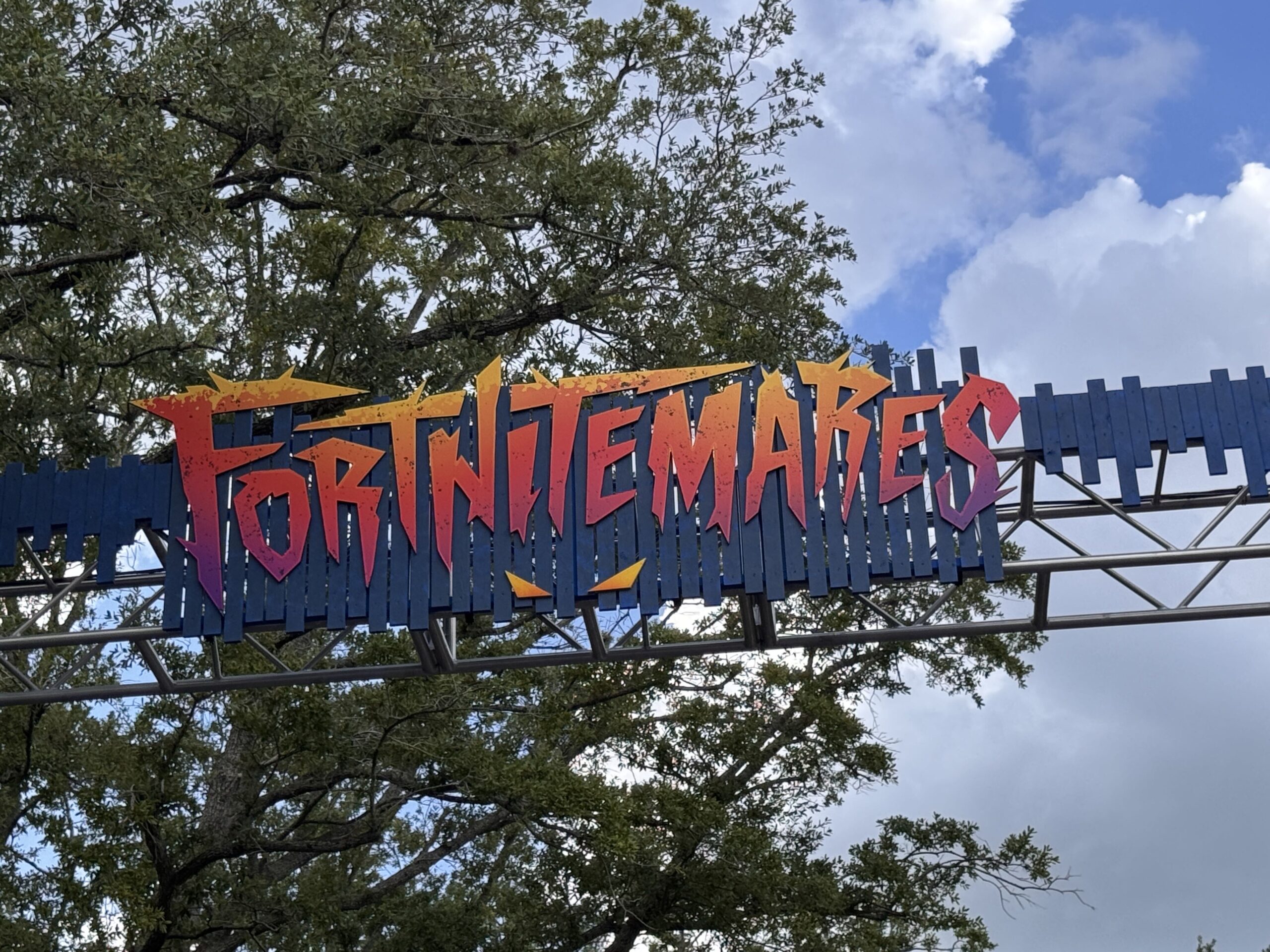 Last but not least for scare zones is FORTNITEMARES in the Central Park area. Trusses at the entrance are adorned with blue paneling and tentacle-like elements. A "FORTNITEMARES" sign is at the top.
