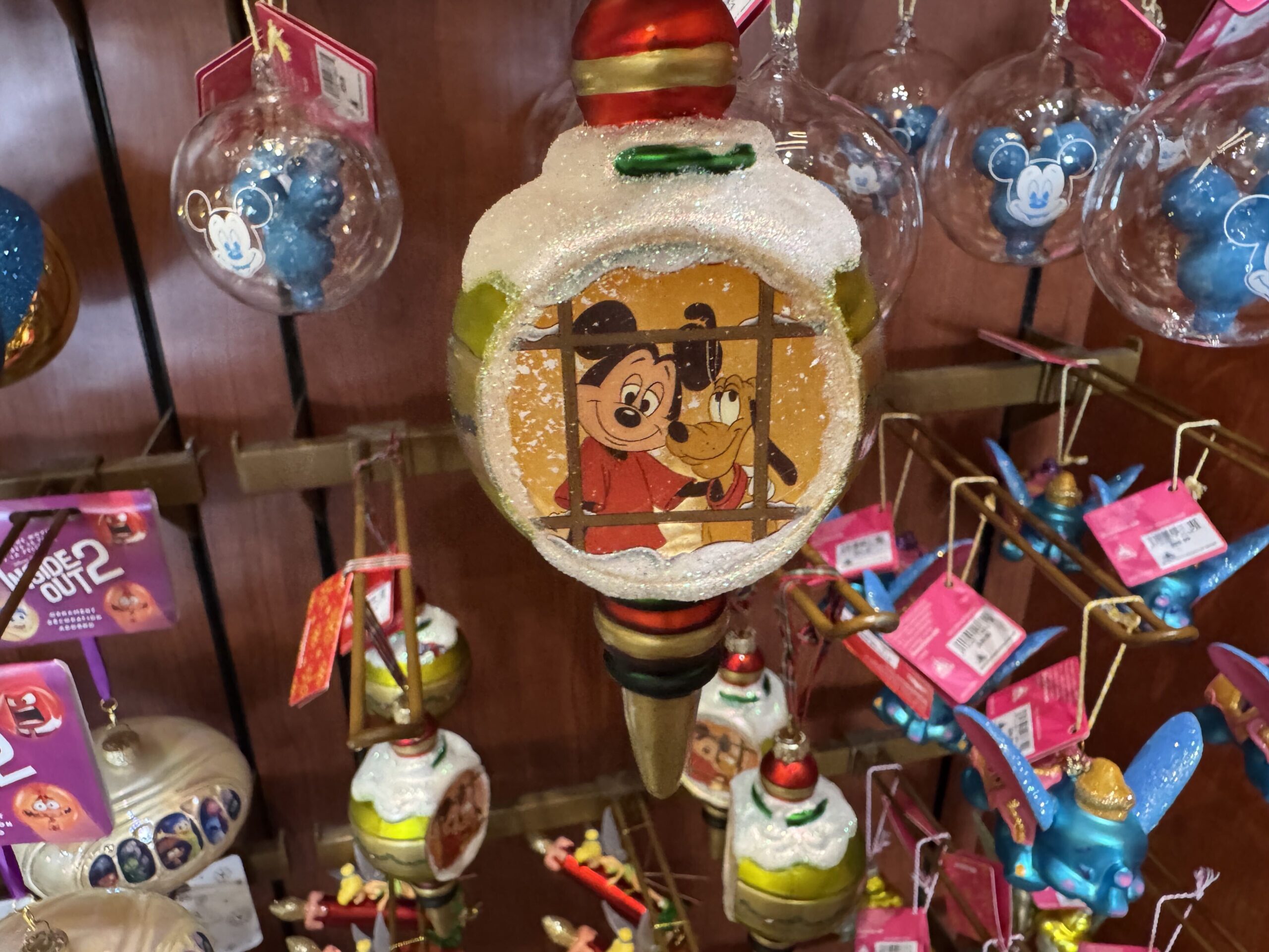 Dumbo flies in bright, cheery colors of blue, orange, and pink. His ears, hat, and saddle holding presents sparkle with glitter. He is crafted of porcelain and painted with rosy cheeks in a watercolor style. 